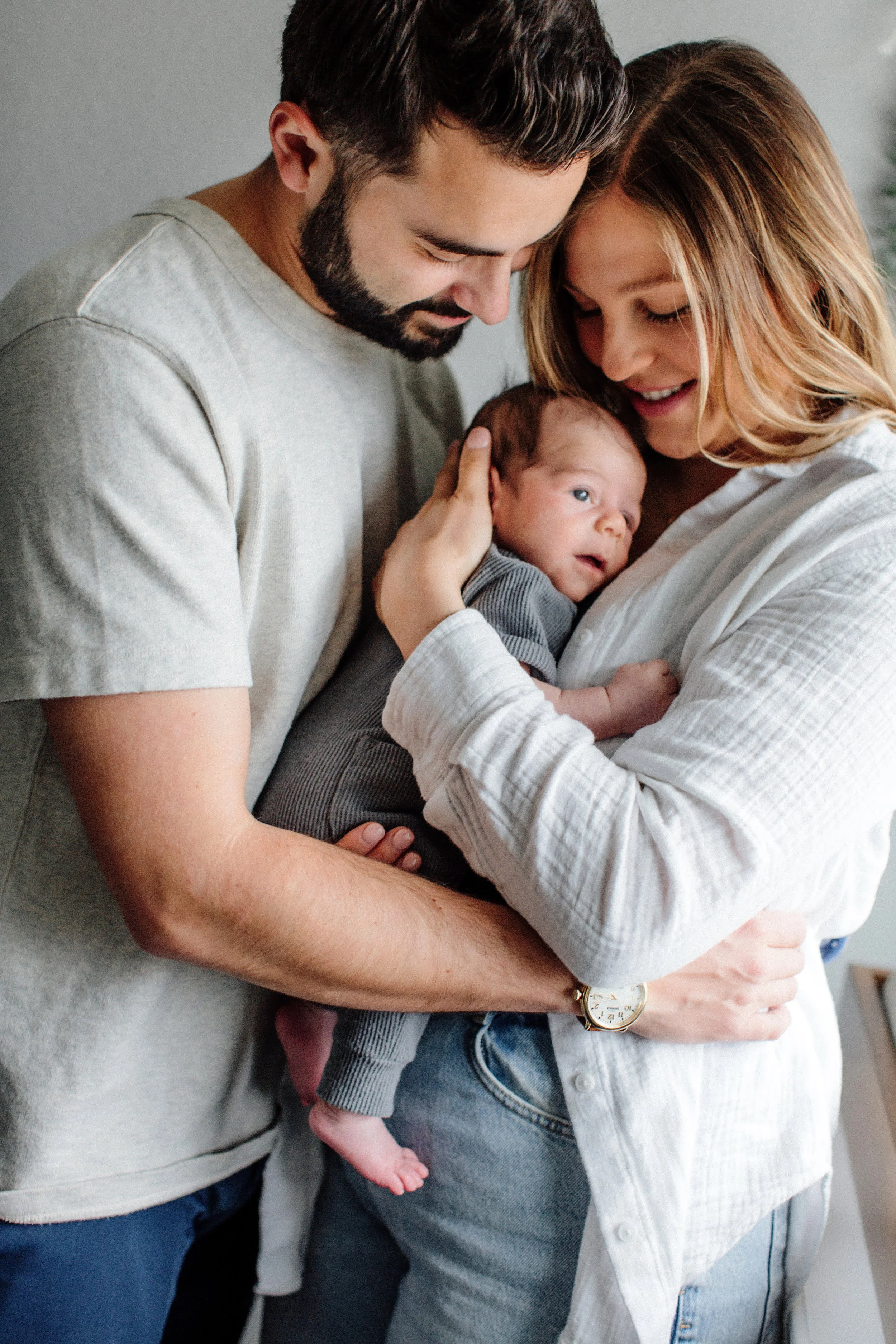 new parents snuggling newborn in nursery during Denver Lifestyle Newborn Photo session in home with new baby