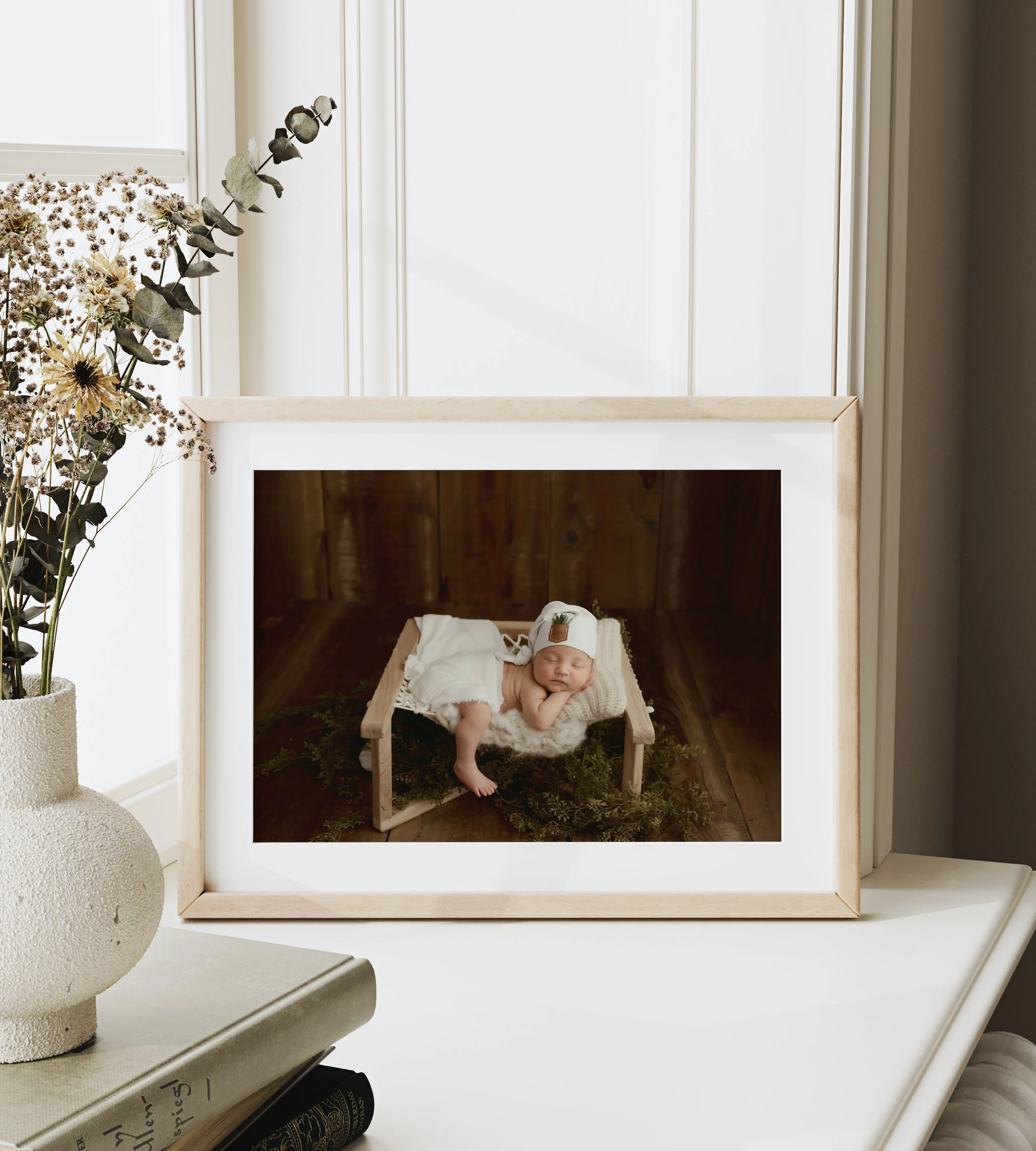A professional newborn photography session featuring a baby wrapped in organic neutral fabrics