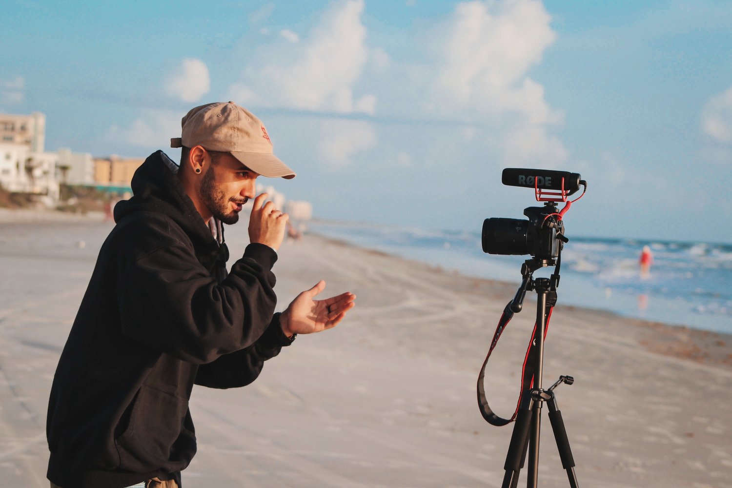 young man filming himself on a beach