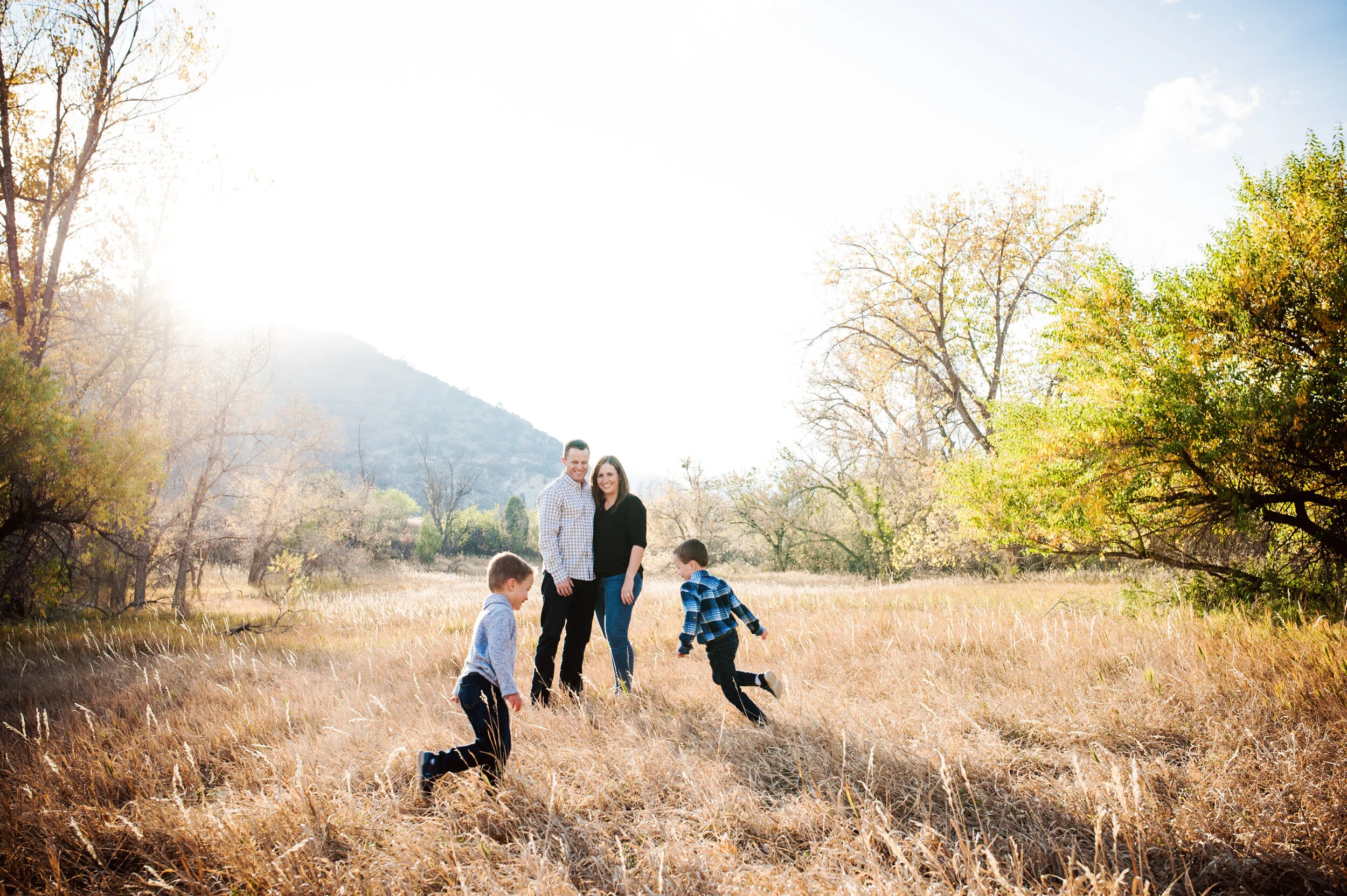 2 boys run in a field as parents watch them in a gorgeous open space in colorado for family photos