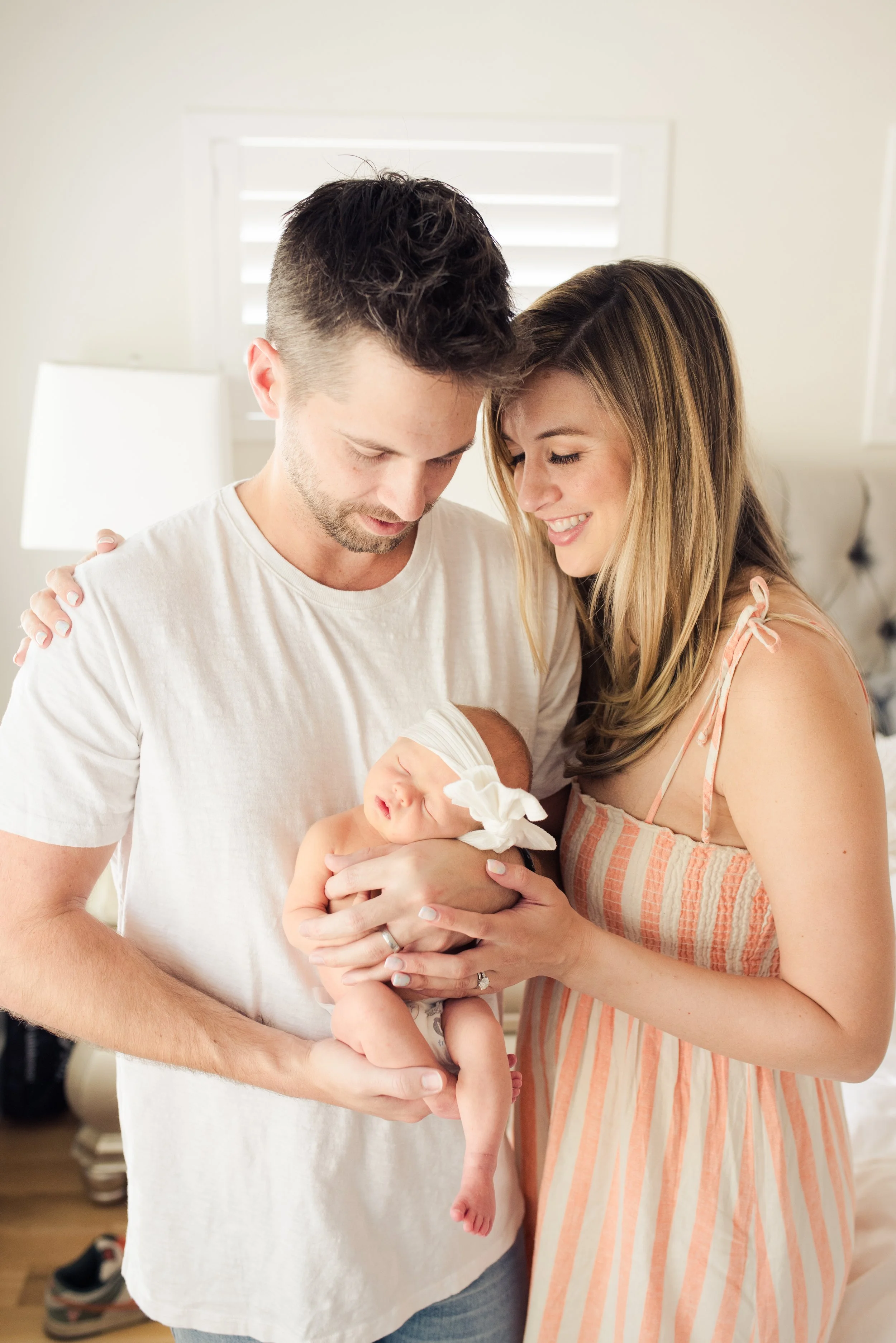 Newborn girl with parents posed by window in their home by a Denver Photographer