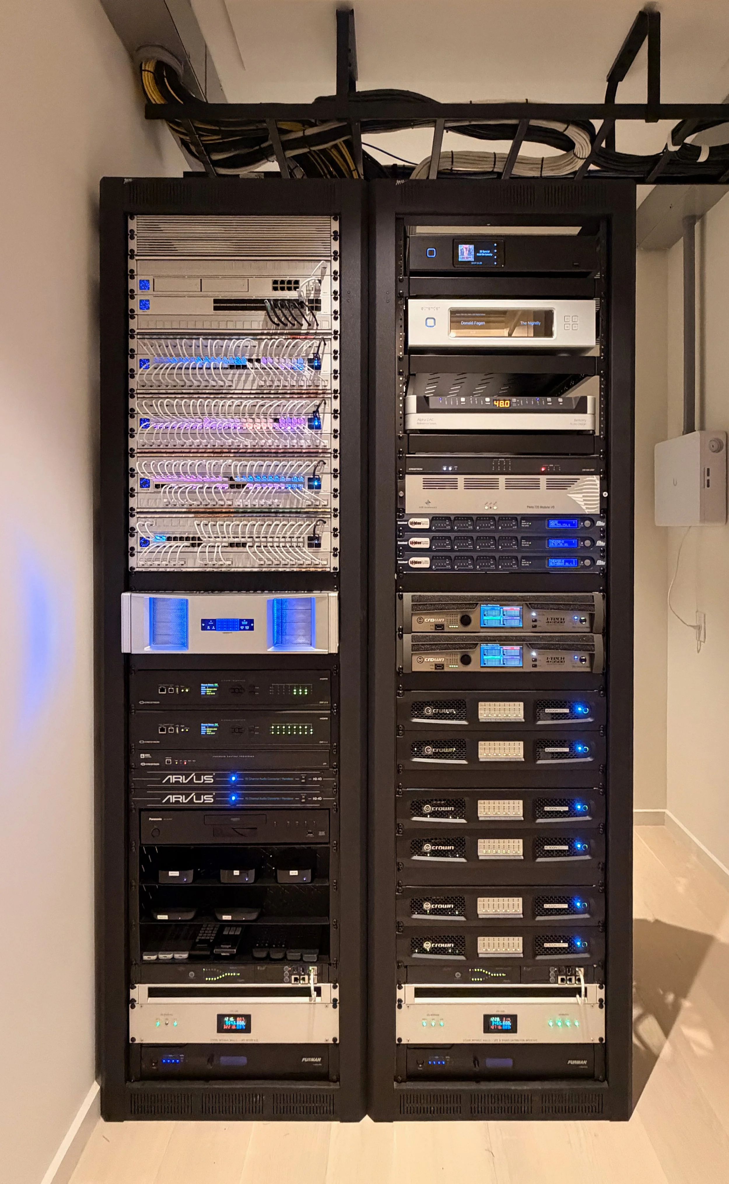 Two server racks filled with networking and computer hardware equipment, including switches, routers, and servers, installed in a data center with cables running overhead.