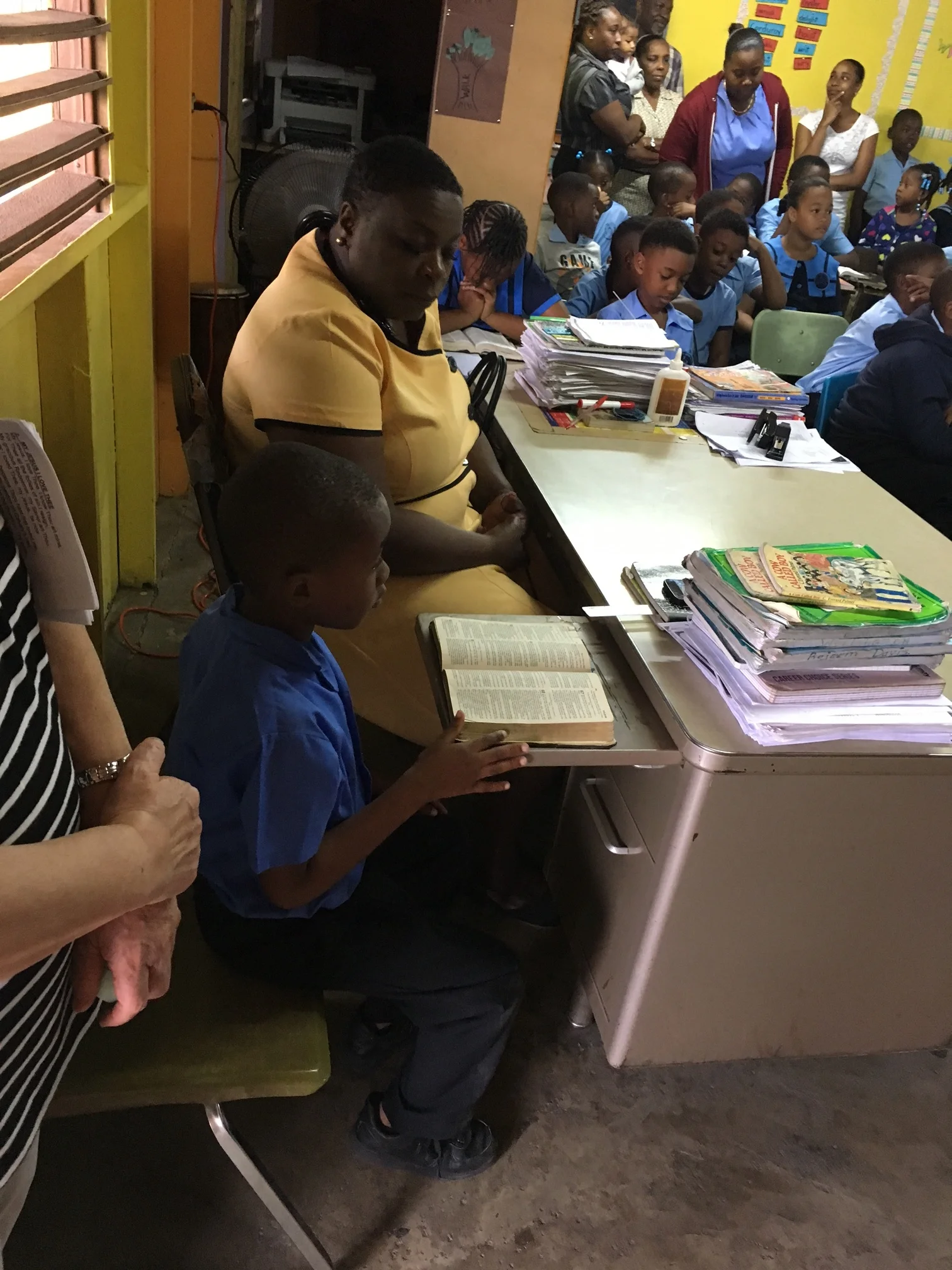 Children read along as Clara reads from the Bible. 