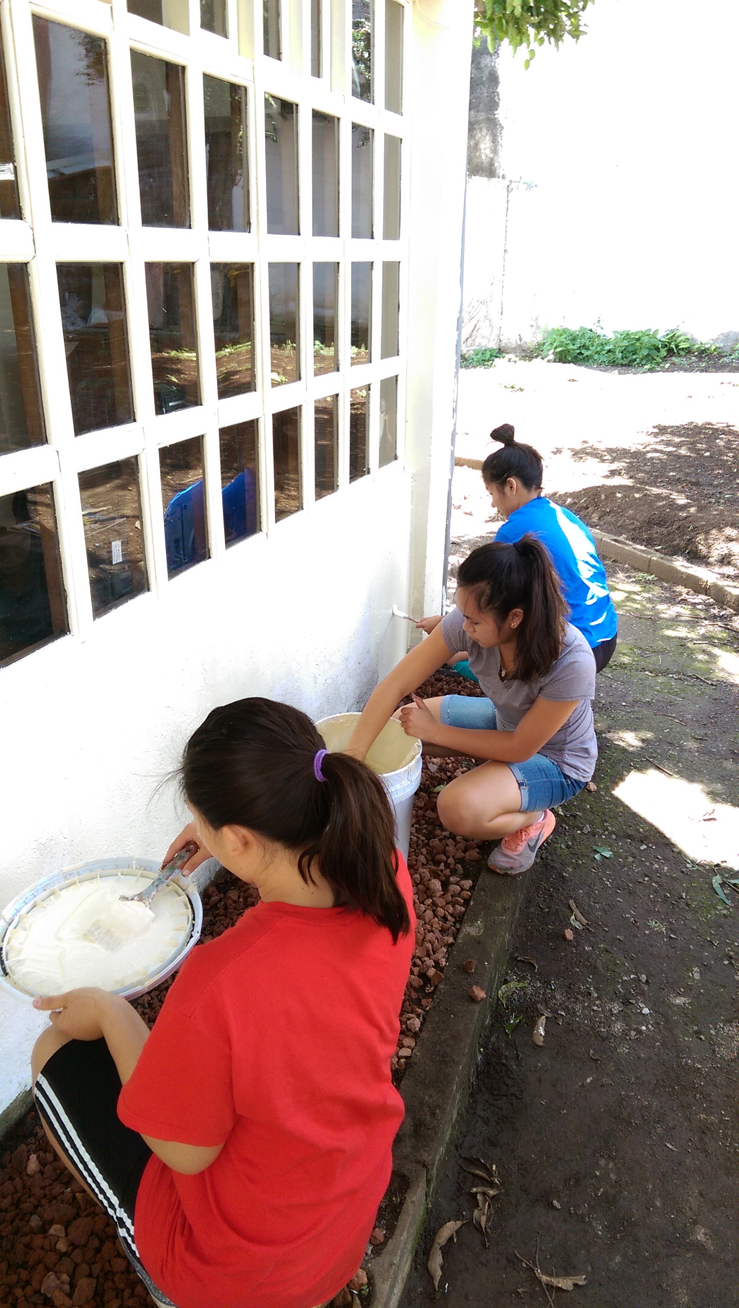 Danielle, Amy, and Lisa painting the wall of the house