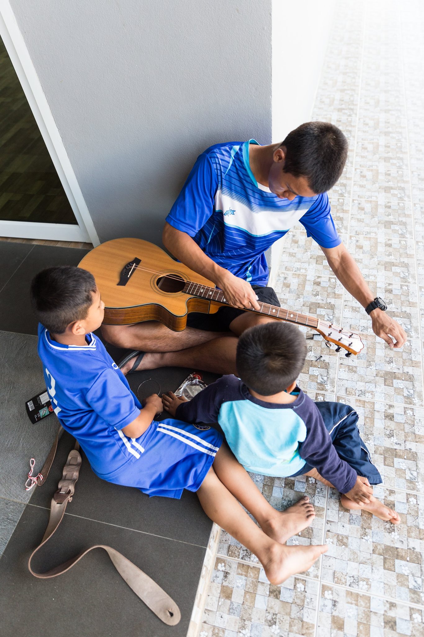 Younger kids watching Traipob work on the guitar