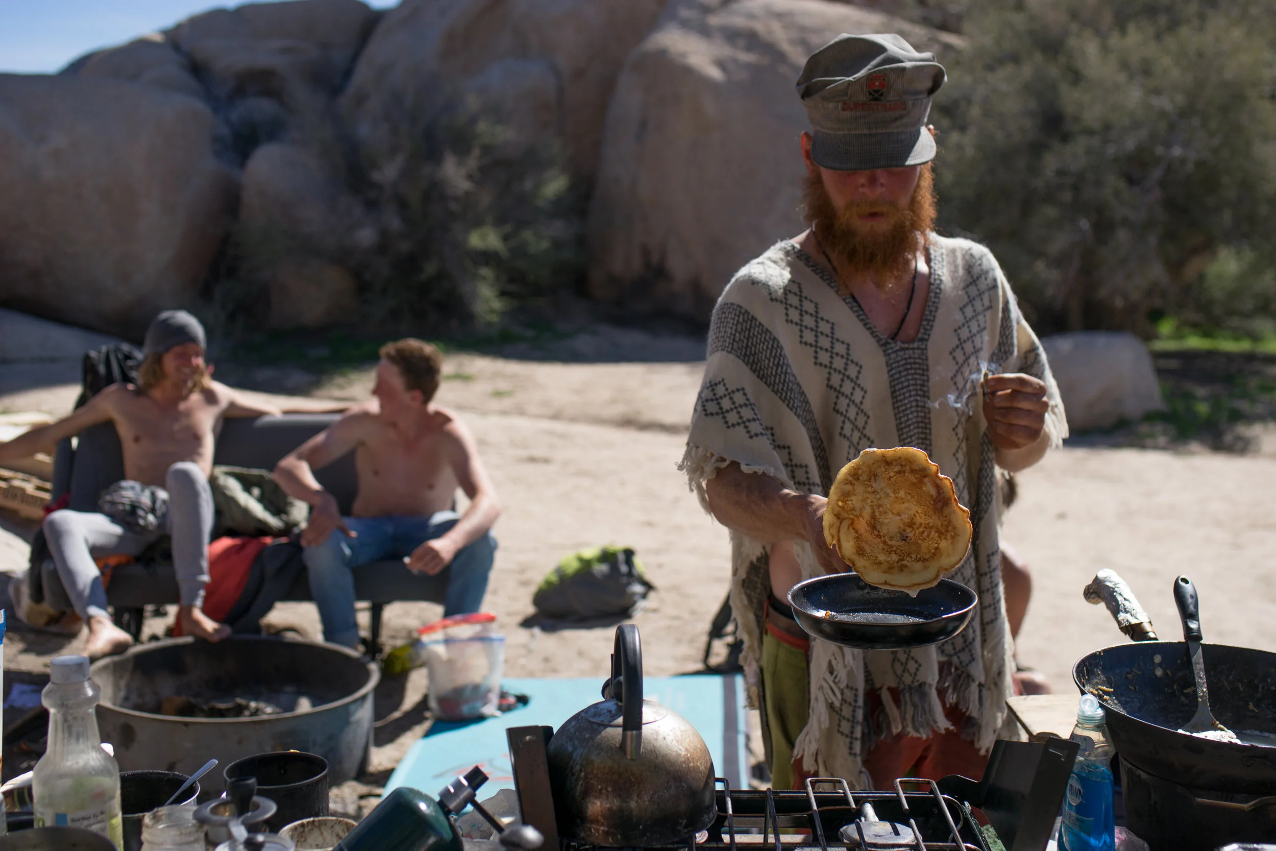 A climber cooks breakfast from the previous night's leftovers, while climbers from other campsites socialize around the campfire. 