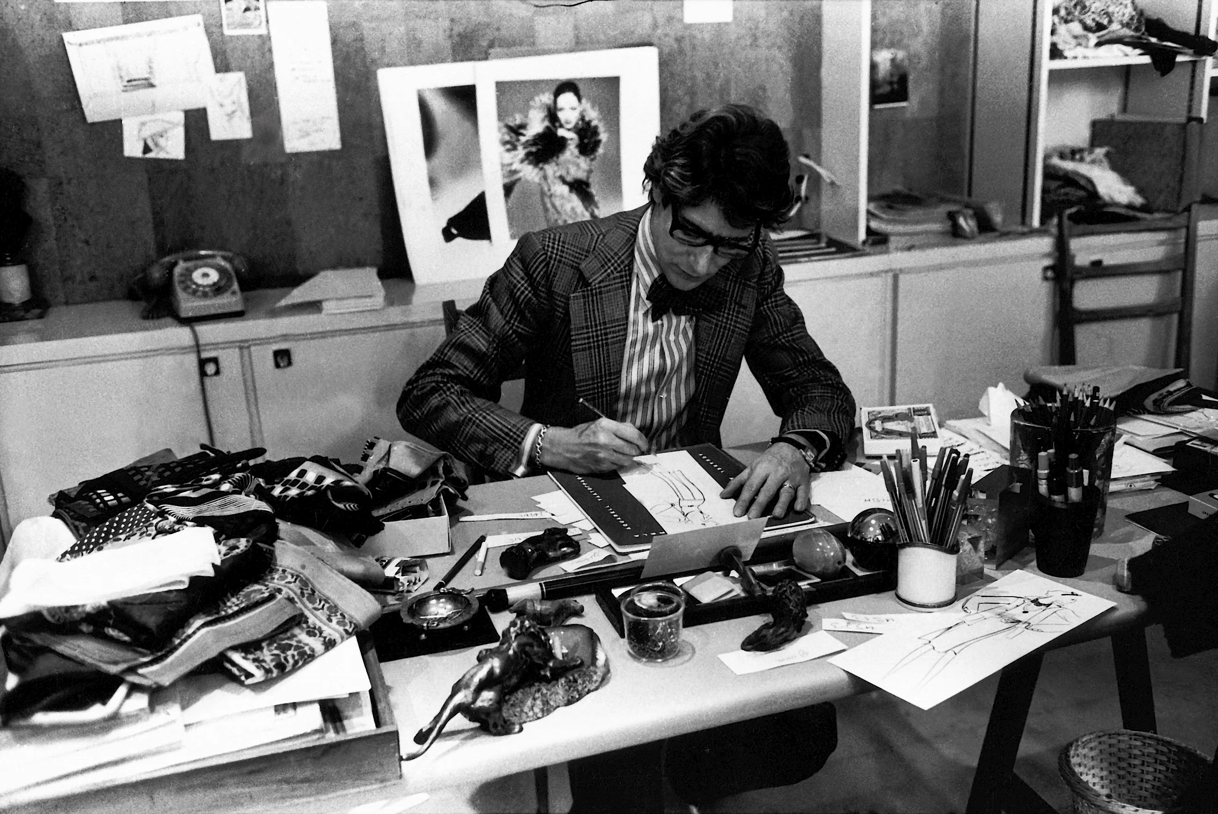  The couturier at work in 1976 in his studio 5 avenue Marceau, Paris. © Fondation Pierre Bergé – Yves Saint Laurent, Paris / Guy Marineau. 