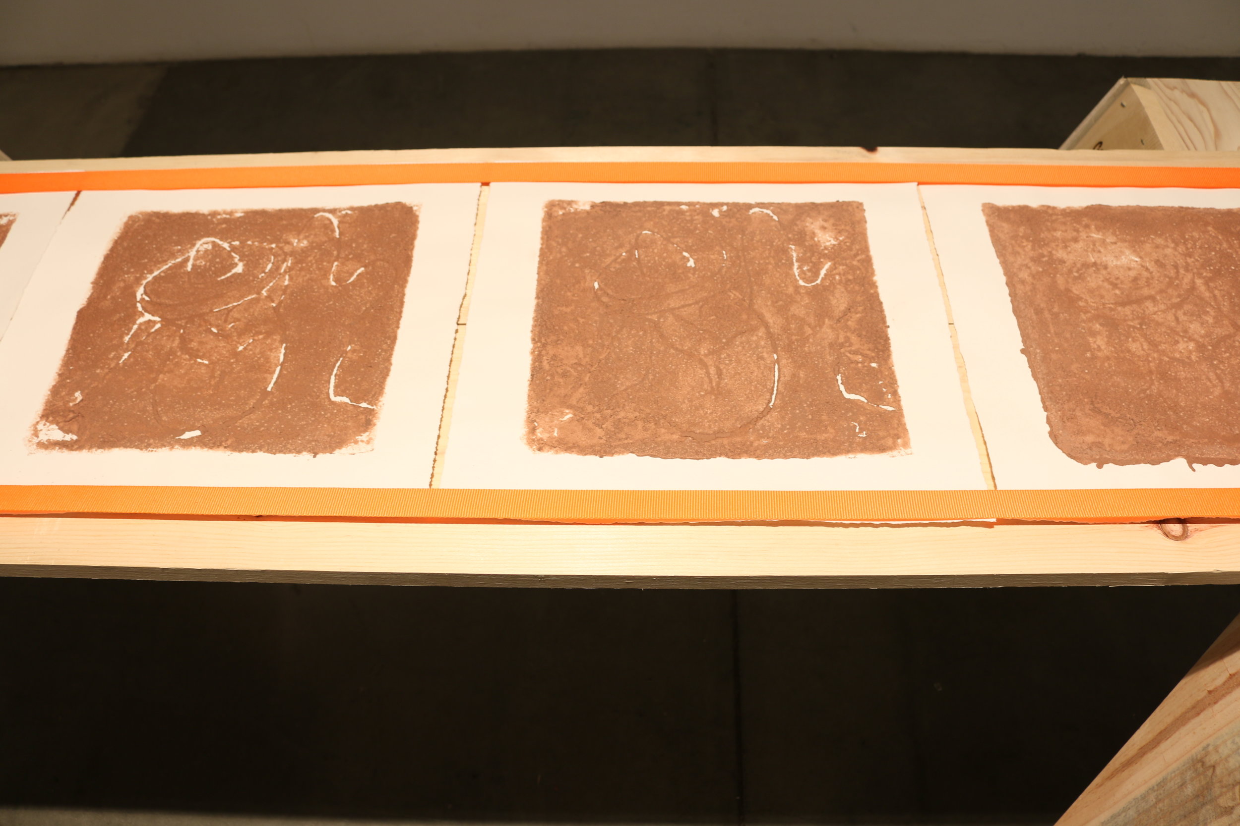   la mancha , 2018   sawhorses, common board, orange furniture straps, terracotta clay, arches archive paper. 24” x 3’ x 8’ 