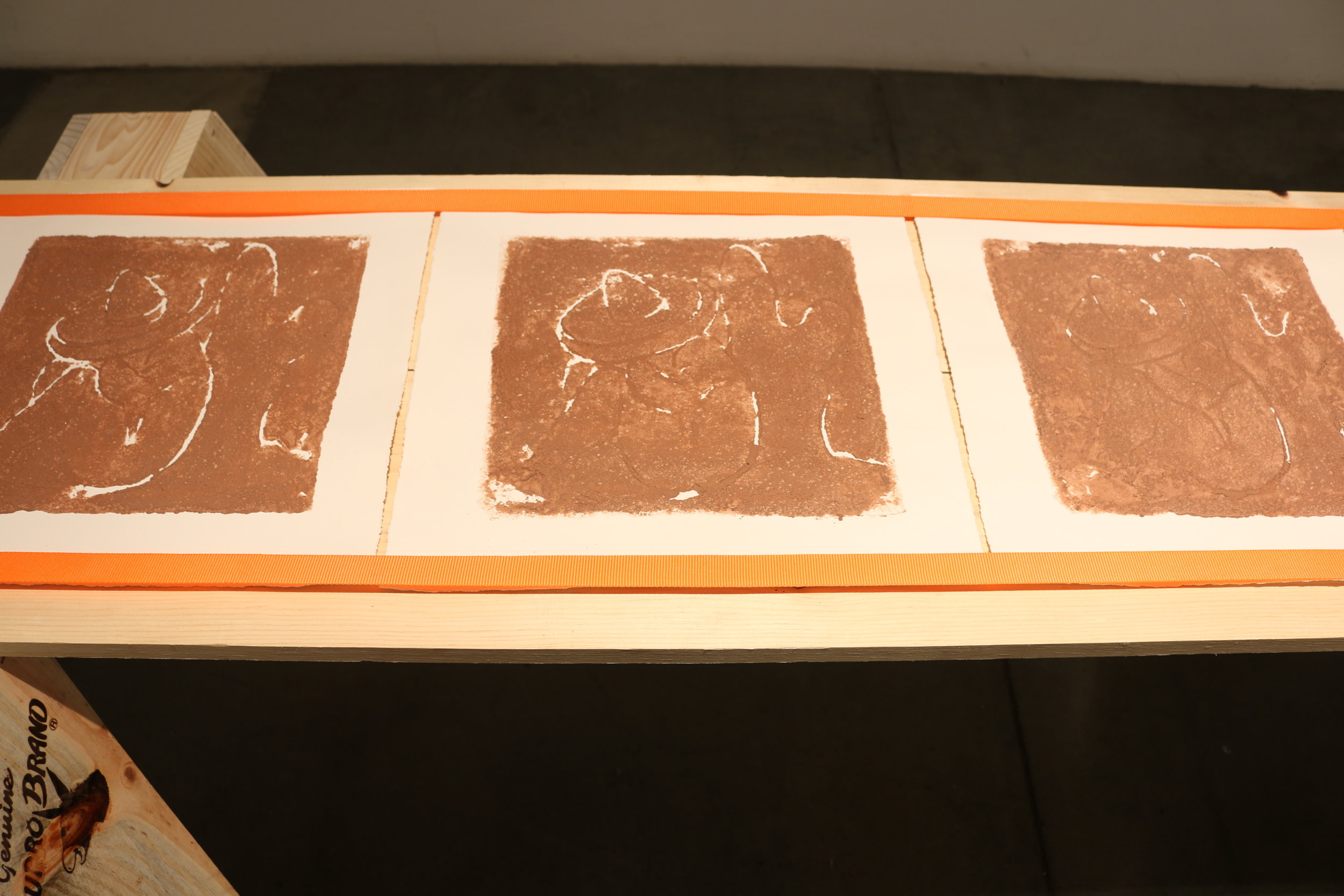   la mancha , 2018   sawhorses, common board, orange furniture straps, terracotta clay, arches archive paper. 24” x 3’ x 8’ 