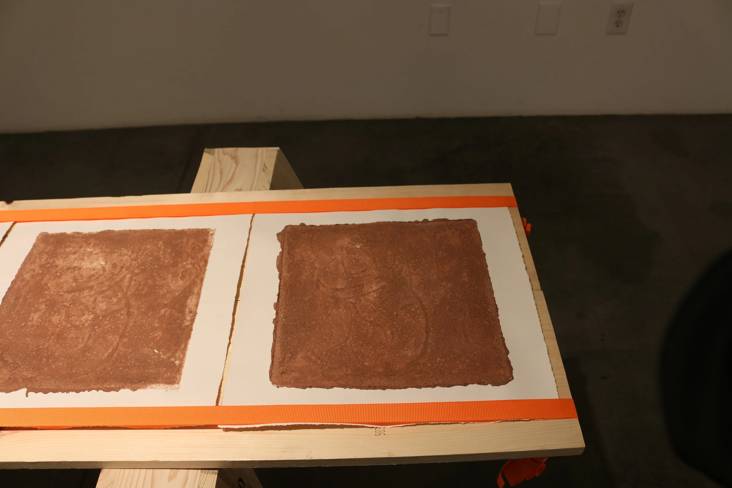   la mancha , 2018   sawhorses, common board, orange furniture straps, terracotta clay, arches archive paper. 24” x 3’ x 8’   