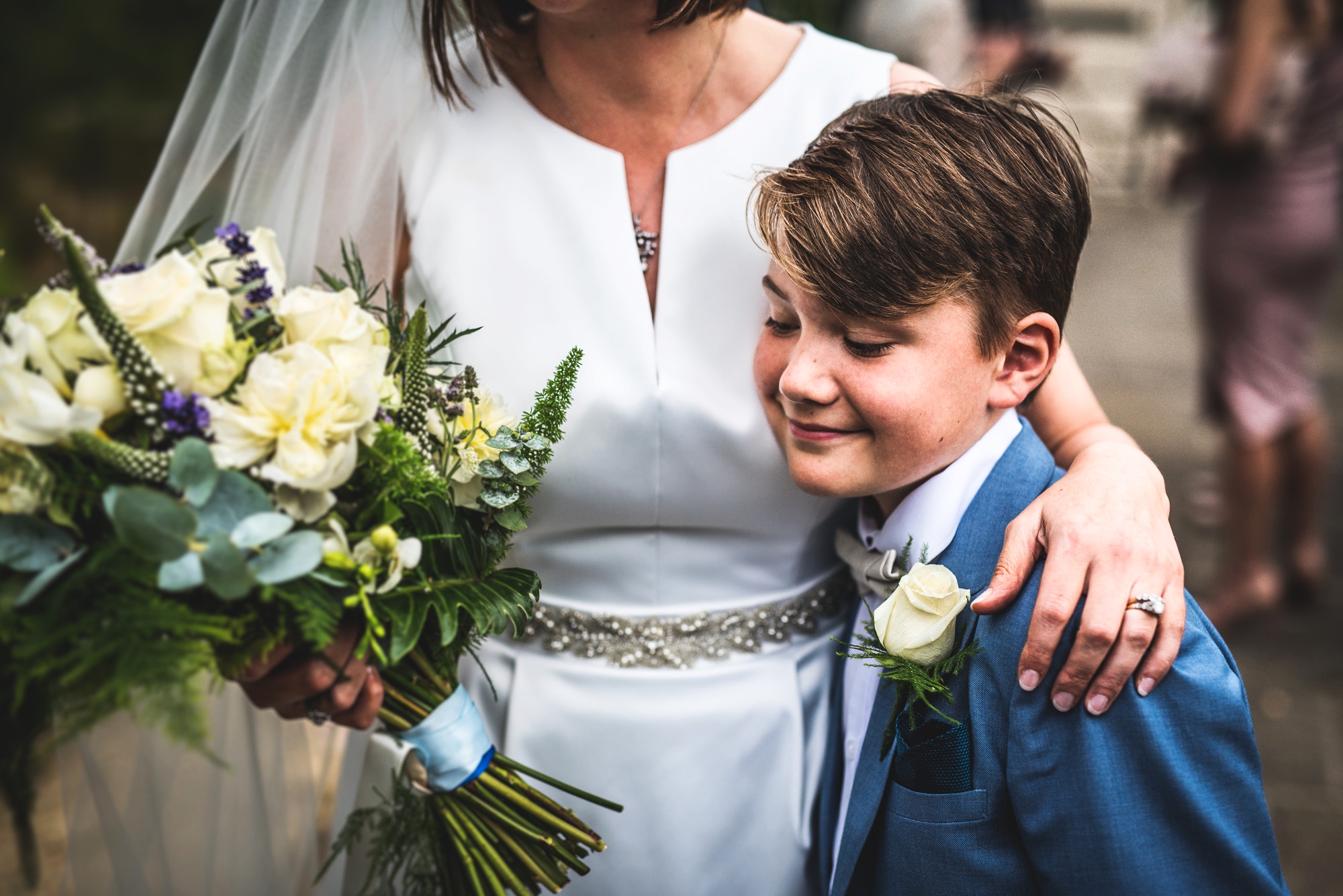 Page boy cuddling bride on her wedding day,Cotswolds, Gloucestershire