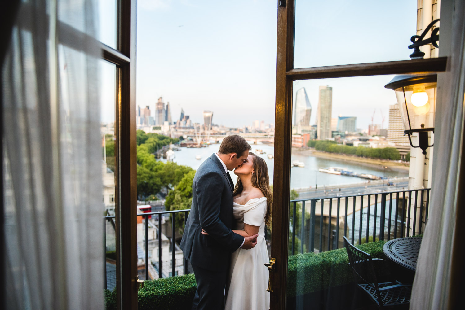 couple embrace on balcony at savoy hotel overlooking river thames and london