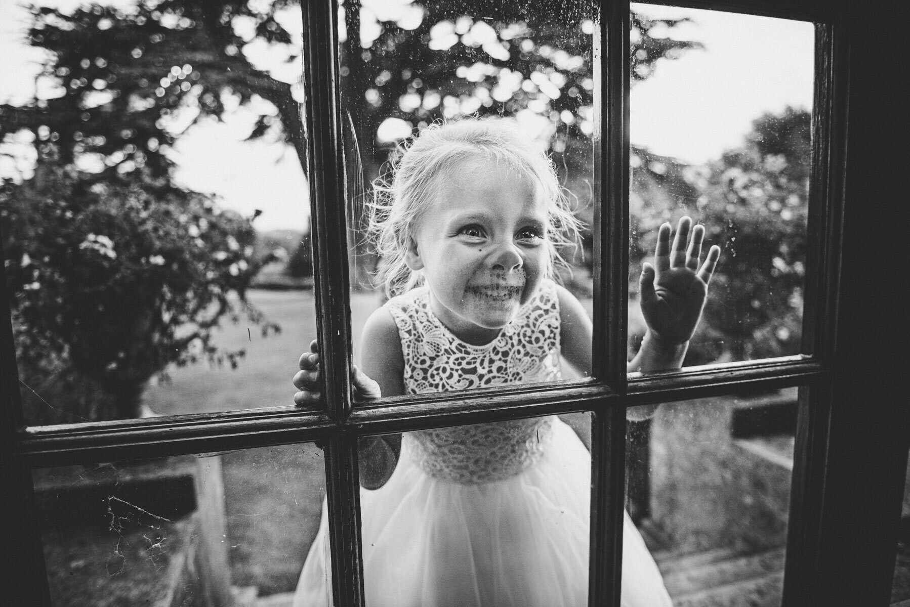 flower girl presses nose against window at hedsor house