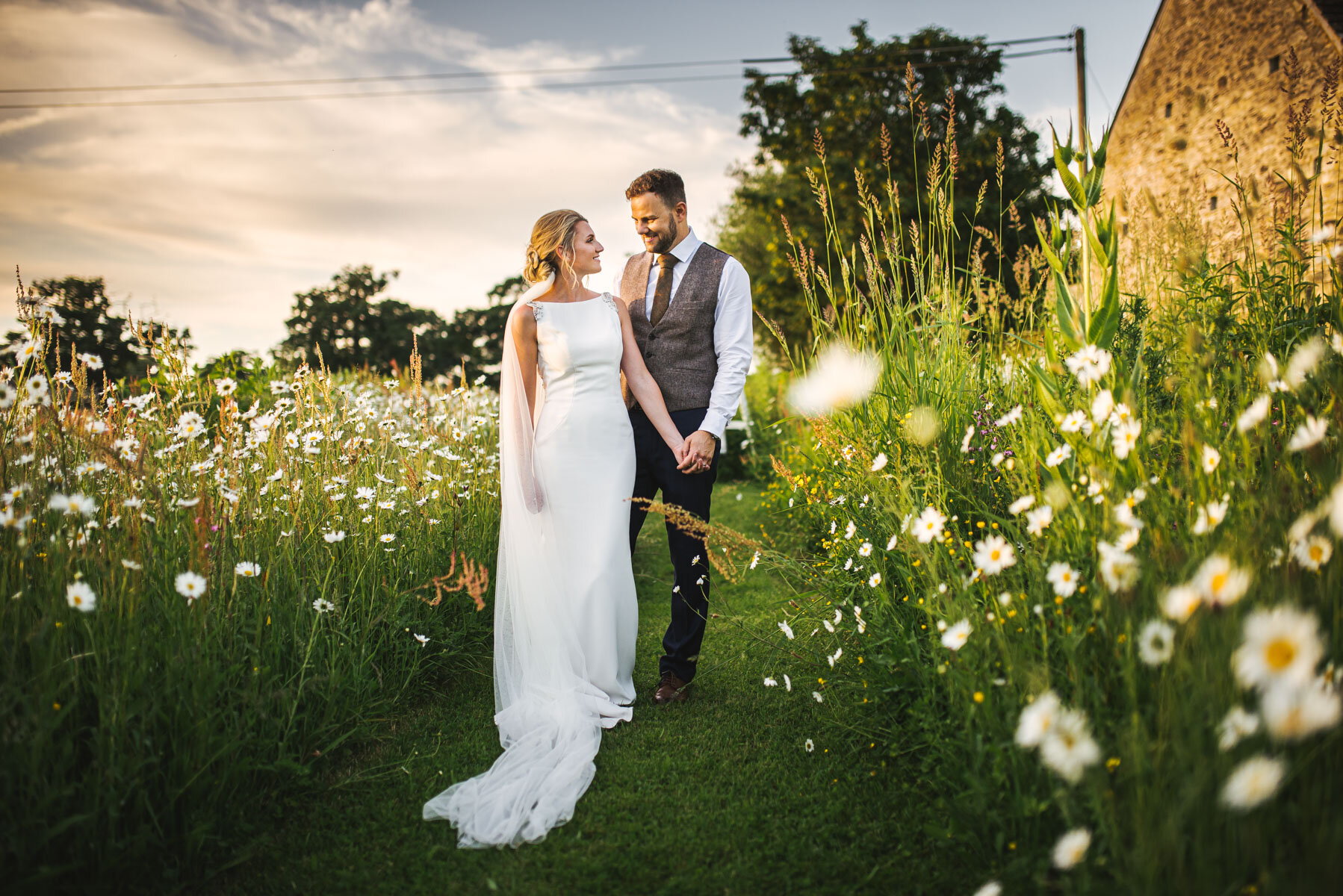 just married bride and groom stood in field surrounded by white flowers