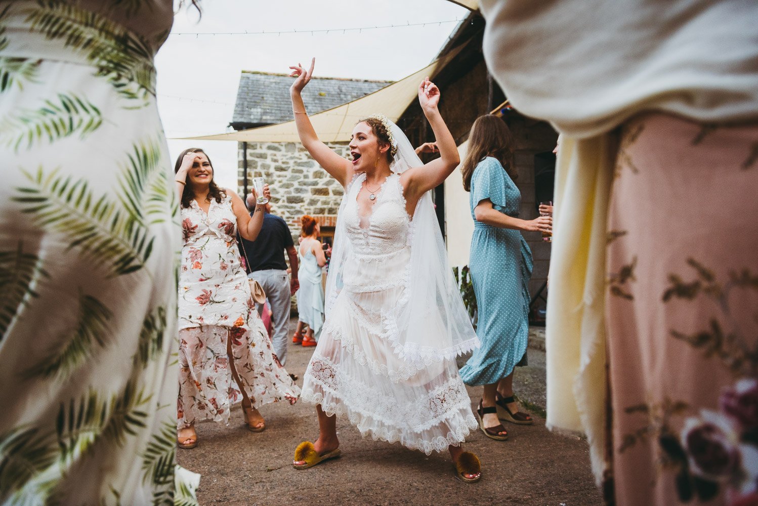bride wearing slippers dances outside with her friends
