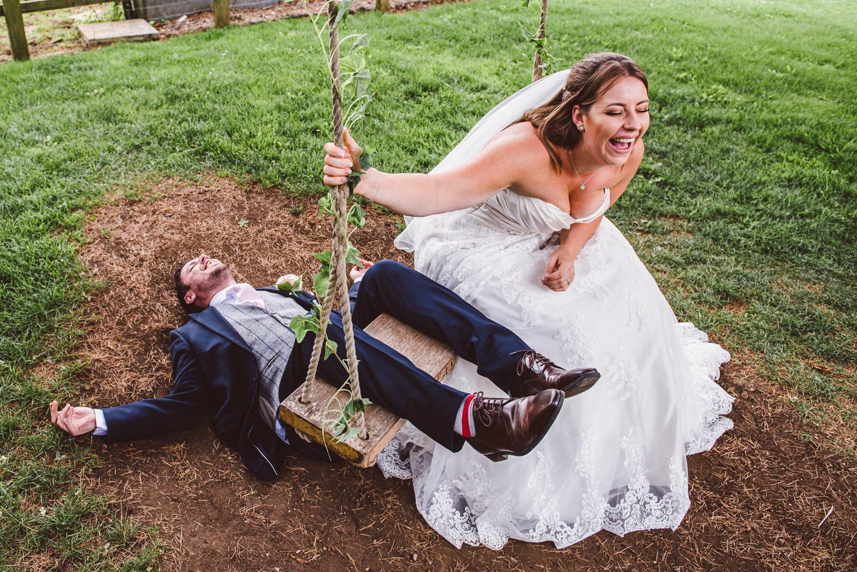 A bride laughs at her groom after he falls off a swing onto his back