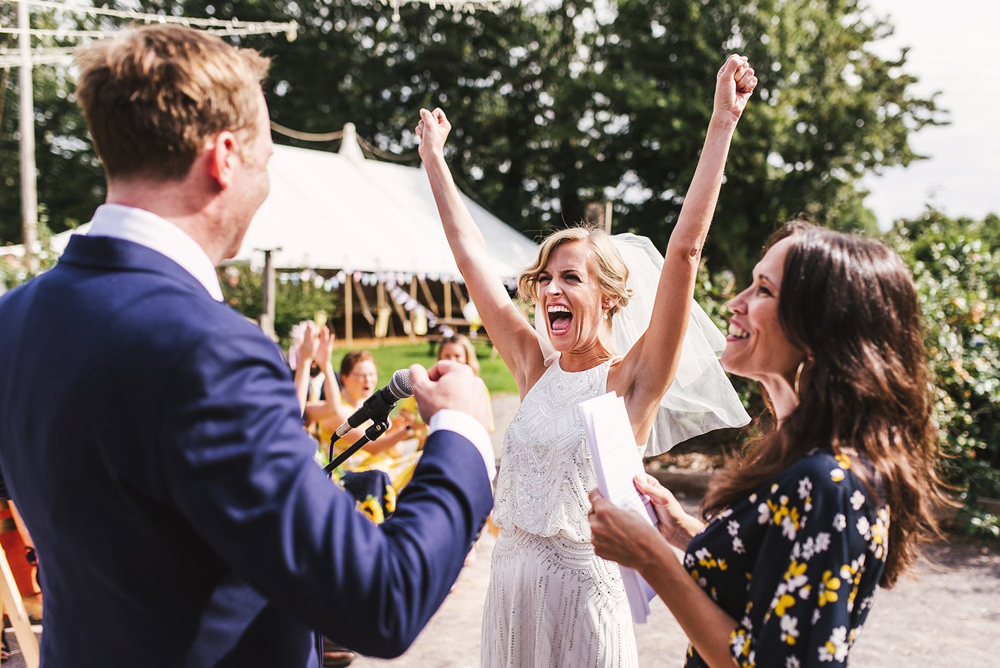 bride with arms outstretched during outdoor pub wedding ceremony in tetbury