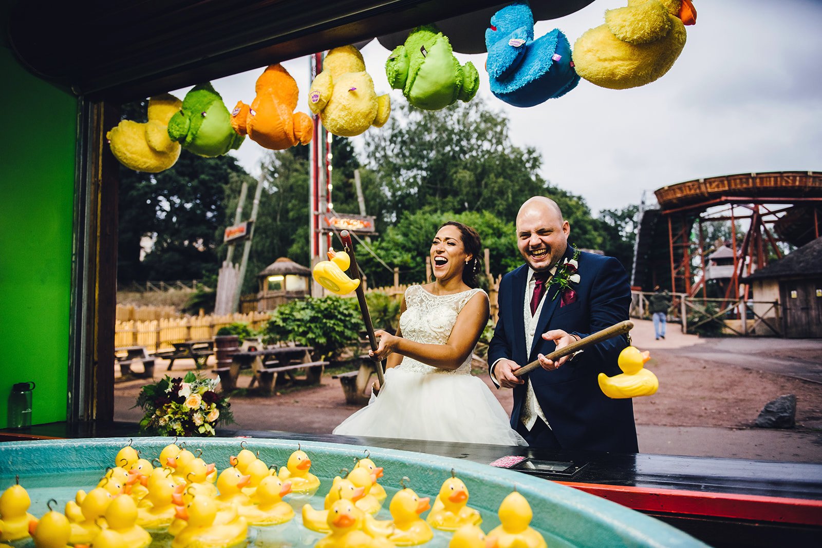 bride and groom laugh as they play hook the duck at west midlands safari park