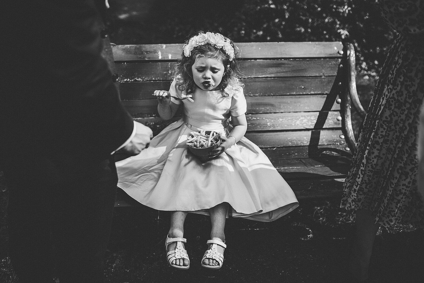 flower girl siting on bench eating chips