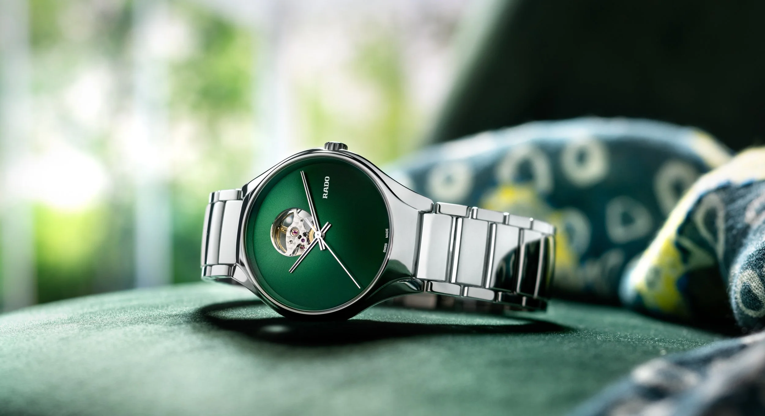 Visuel pub pour Rado : Montre avec cadran vert et bracelet en métal, posé sur fauteuil vert