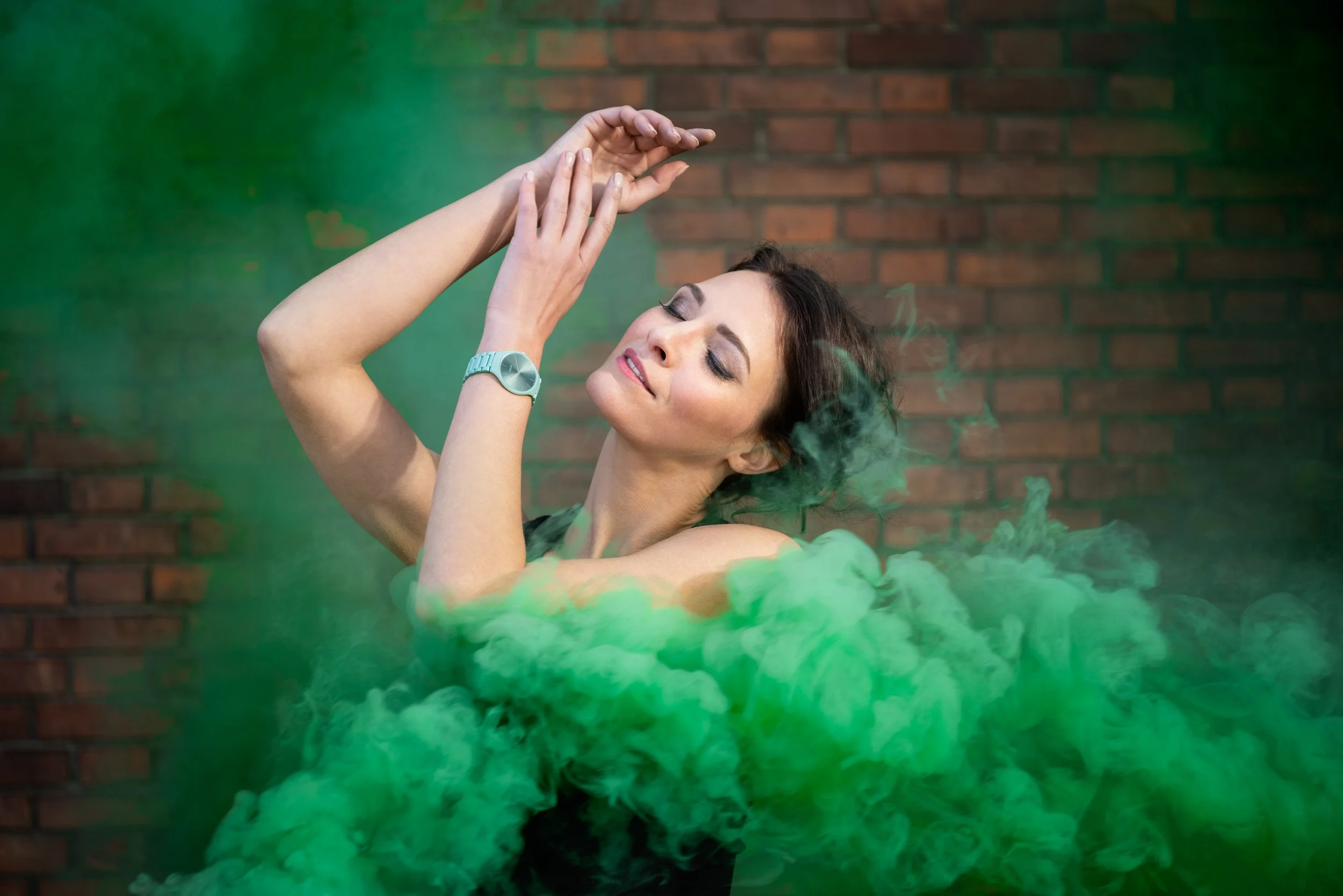 Visuel pub pour Rado : Femme en train de danser avec fumigène de couleur verte autour d'elle, contre un mur en briques.