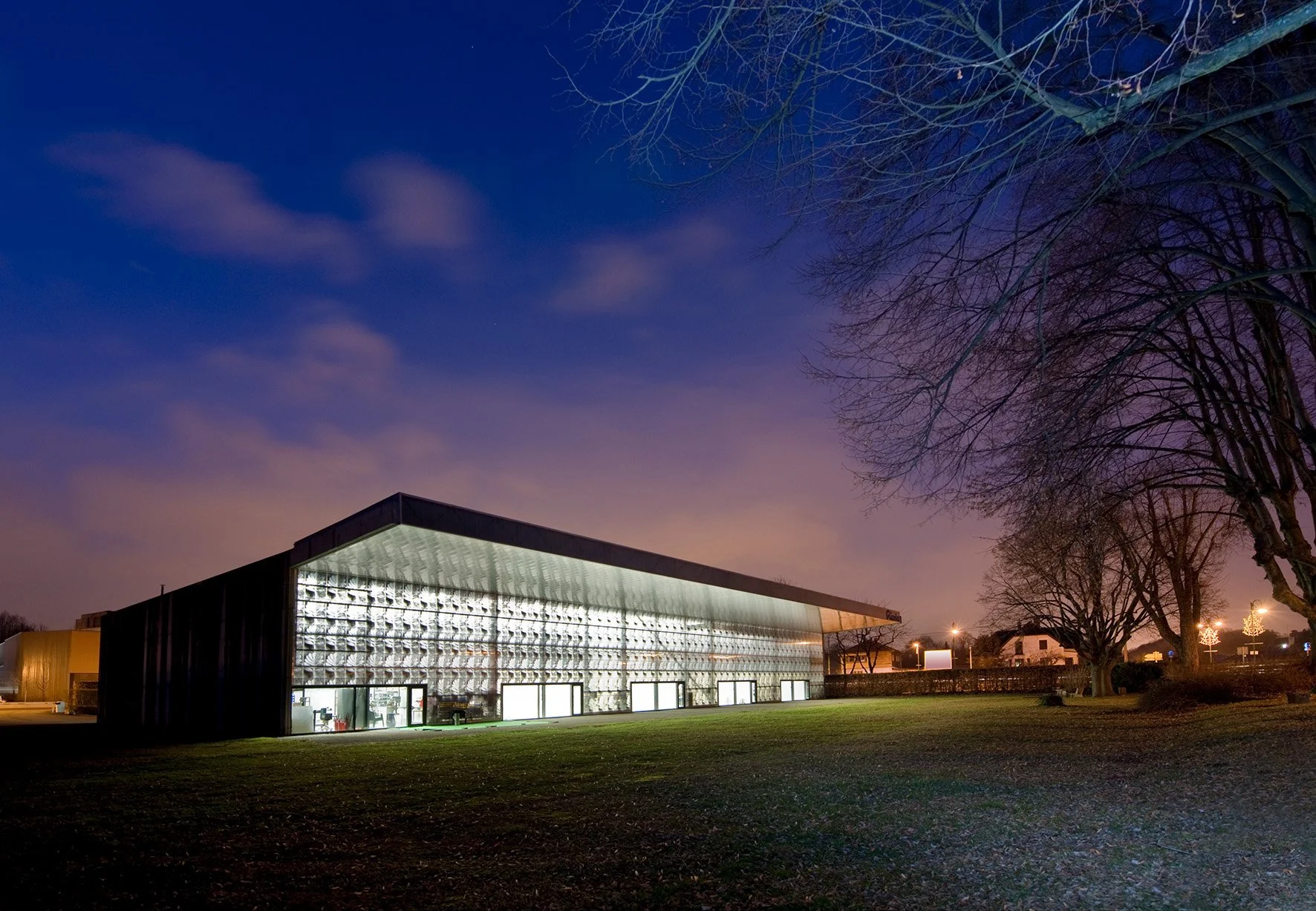Photographie d'architecture: Bâtiment moderne éclairé la nuit avec un ciel étoilé 