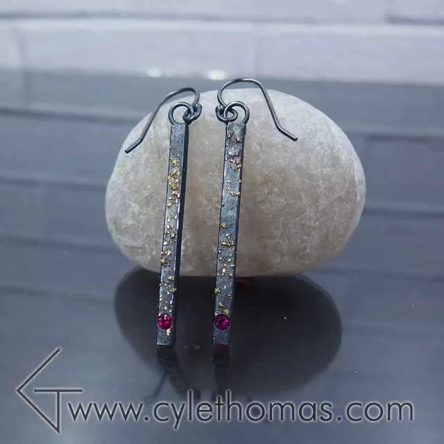  These earrings hail from the Spacescapes collection.&nbsp; The 22K fused gold filings represent stars against the oxidized sterling silver night sky.  Sterling Silver, 22K Yellow Gold, AAA Rubies  Fabricated, Fused, Flush Set, Oxidized&nbsp; 