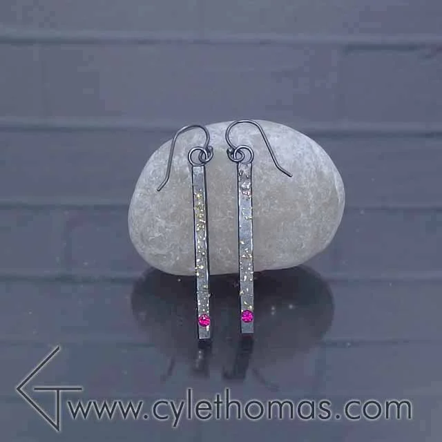  These earrings hail from the Spacescapes collection.&nbsp; The 22K fused gold filings represent stars against the oxidized sterling silver night sky.  Sterling Silver, 22K Yellow Gold, AAA Rubies  Fabricated, Fused, Flush Set, Oxidized&nbsp; 