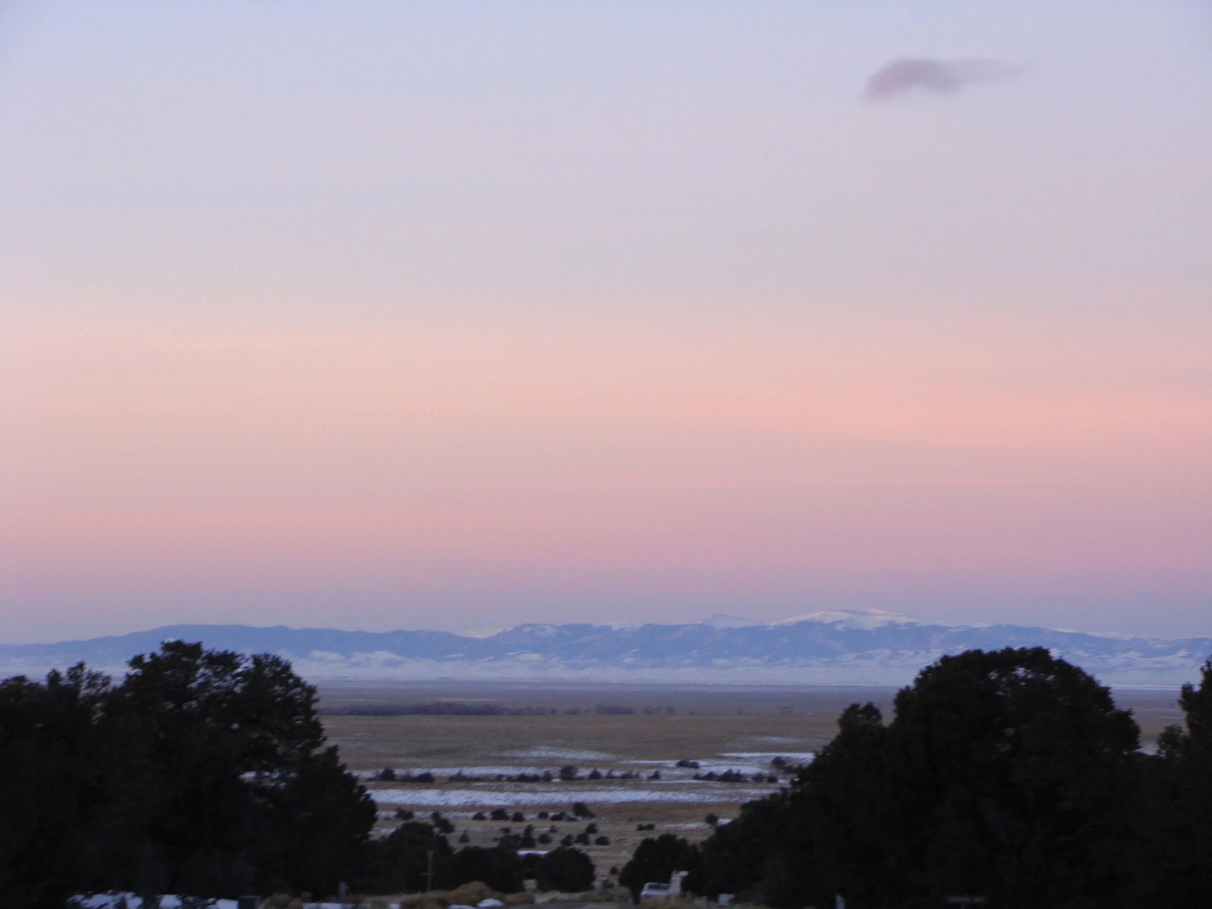 Sunrise lights up the San Juan Mountains across the valley.