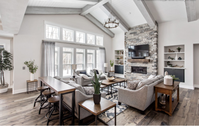 Photo: La Maison Interiors.  The perfect footprint for the living room designates it’s space with the area rug.  Hard to reach windows are easily covered and operated with motorized window coverings and hardwood floors are still the popular choice f…