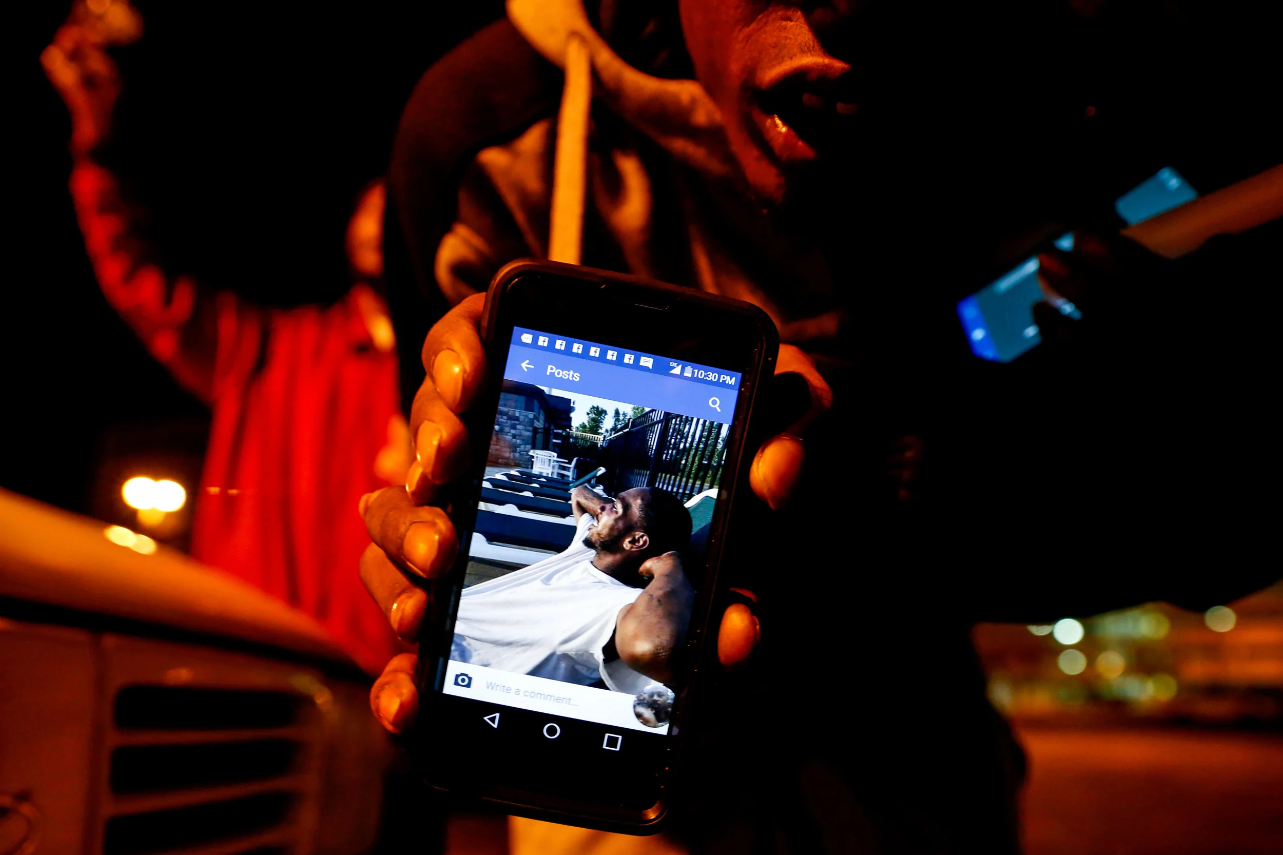 Chola Williams, brother of Donte Williams, holds up one of his favorite pictures of Donte while gathered at a vigil service on Sunday, Oct. 23, 2016 at the Flat Lot in downtown Flint where he died earlier that day after being shot multiple times. "That's Donte looking at us right now," Williams said as he shows a photo of his brother from his phone.