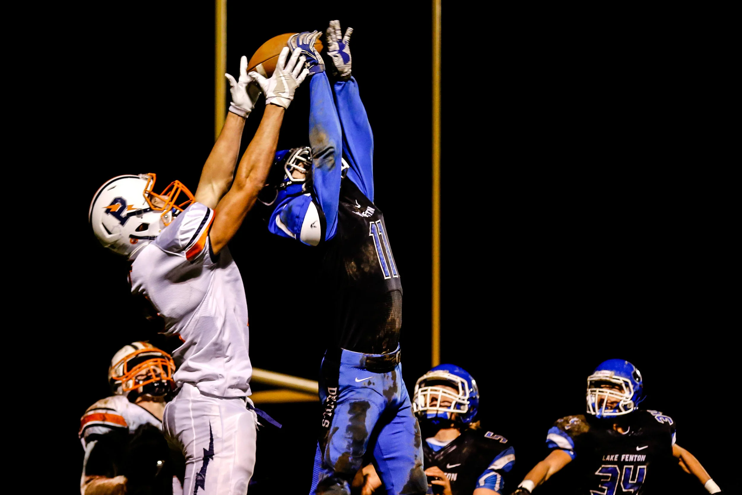 Powers Catholic's Matt Wiskur (12) and Lake Fenton's Matthew Tomczyk (11) reach for the ball during the football game on Friday, Oct. 28, 2016 at Lake Fenton High School in Linden. Powers Catholic defeated Lake Fenton 20-19. 