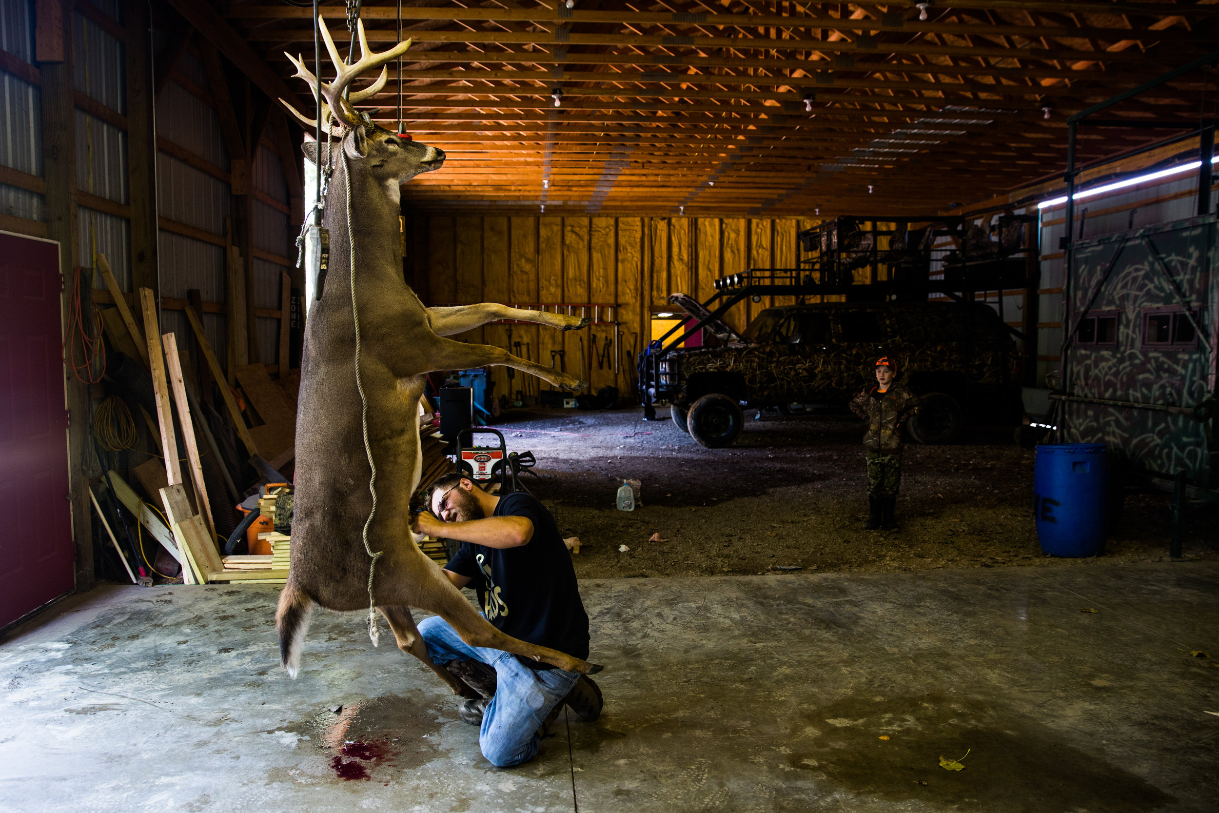 Carson watches from a distance as the buck he shot is gutted and cleaned.&nbsp;  "Watching him shoot a gun at 11, and just being very comfortable and calm...he taught me how to be calm and collected," Paul said. 