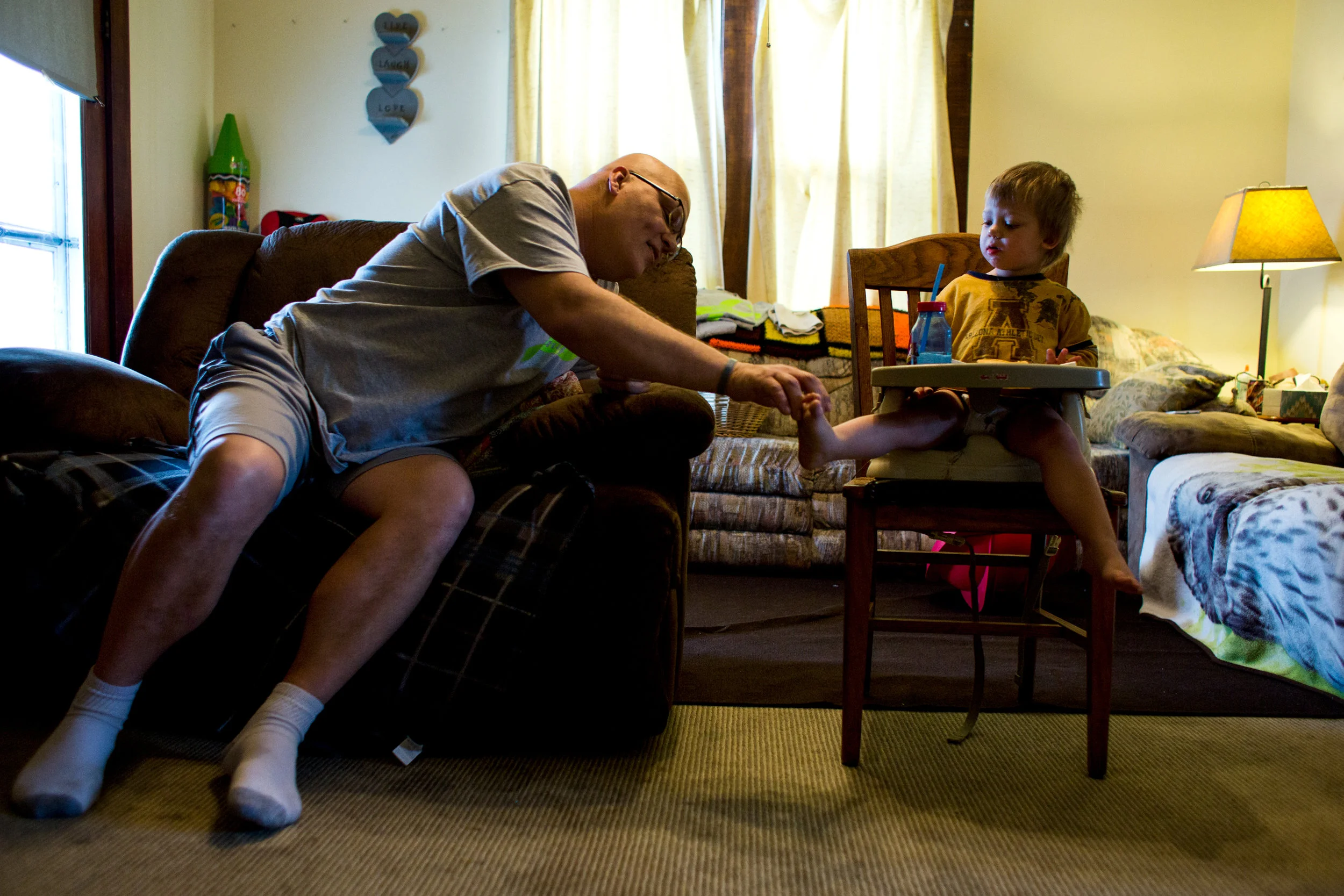 Danny Barnett reached to touch the toes of his son Ethan, 2, on Thursday morning at his home in Jasper. Barnett was diagnosed late last year with an aggressive form of cancer called pleomorphic cutaneous T-cell lymphoma. His condition leaves him with little energy and much of his day is spent sitting in his chair, resting and playing with his son.