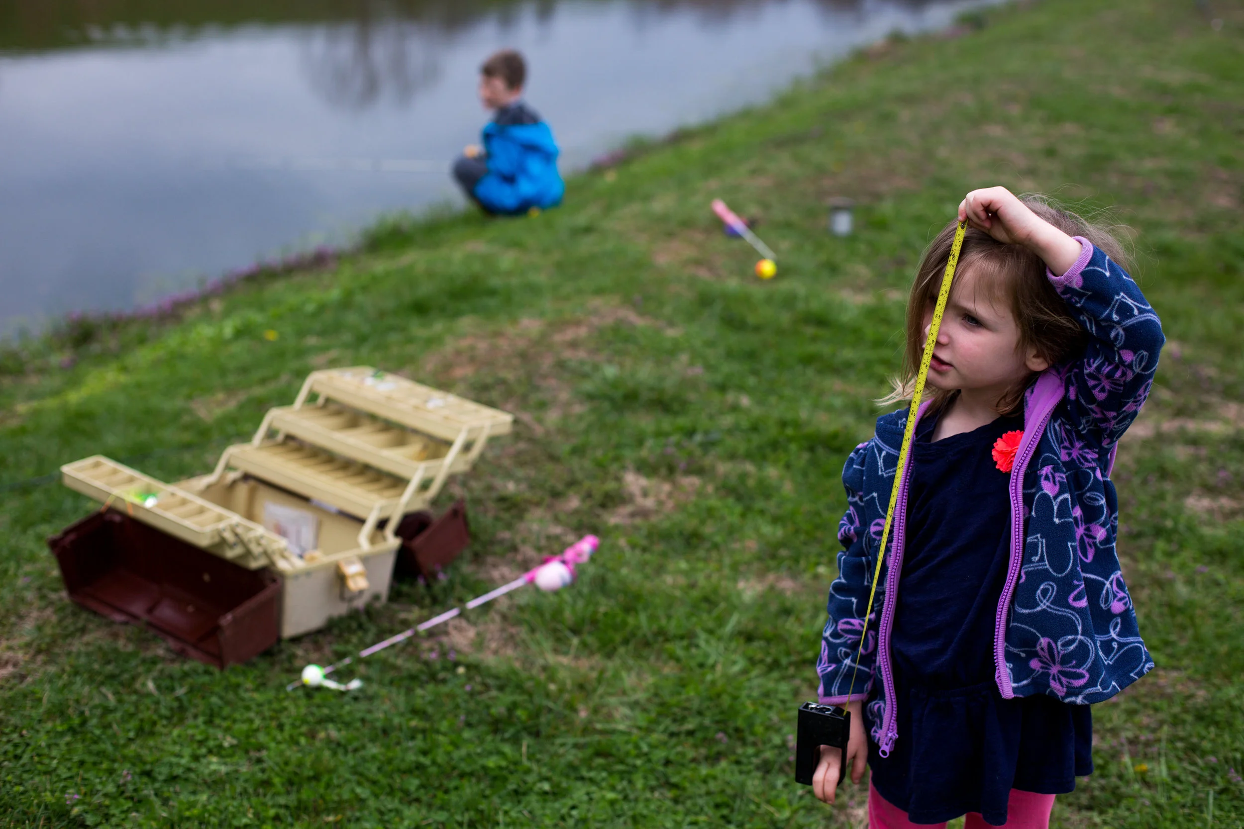 Molly Schepers of Dubois, 4, asked for help in measuring herself while her brother Marshall, 8, fished at their grandmother's pond in Dubois on Tuesday.