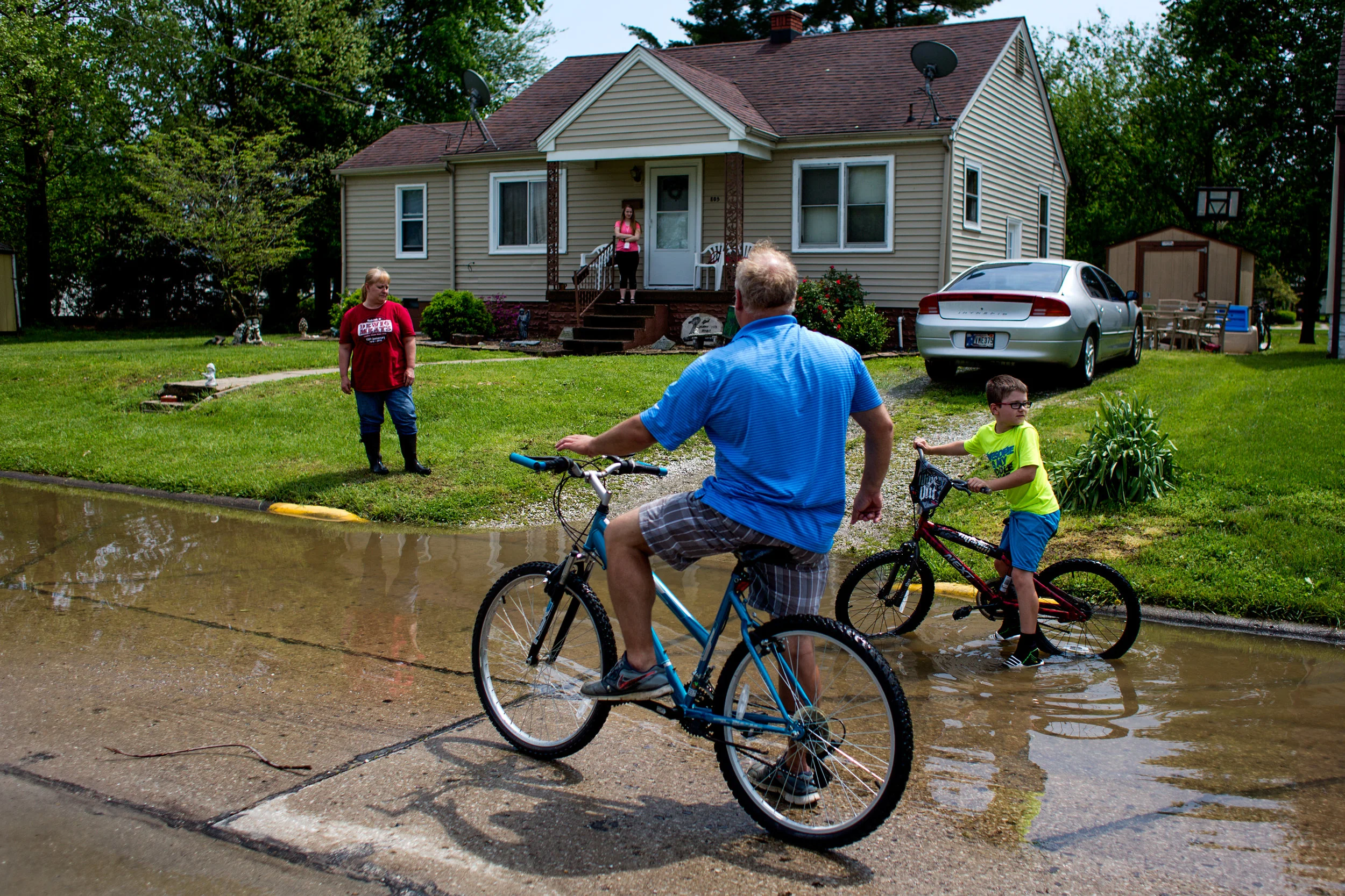 Todd Lau of Huntingburg and his son, Michael, 10, biked over to check on his cousin Kristy Lawrence and her daughter, Kristyn, 16, after storms flooded many of the homes in the Huntingburg neighborhood Saturday. Kristyn recently received her license and bought a car which experienced extreme water damage from the storm. She said that the interior of the car was covered in mud, but the only thing that was not damaged was a box of things from her recently deceased friend, Lexi Mattingly. 