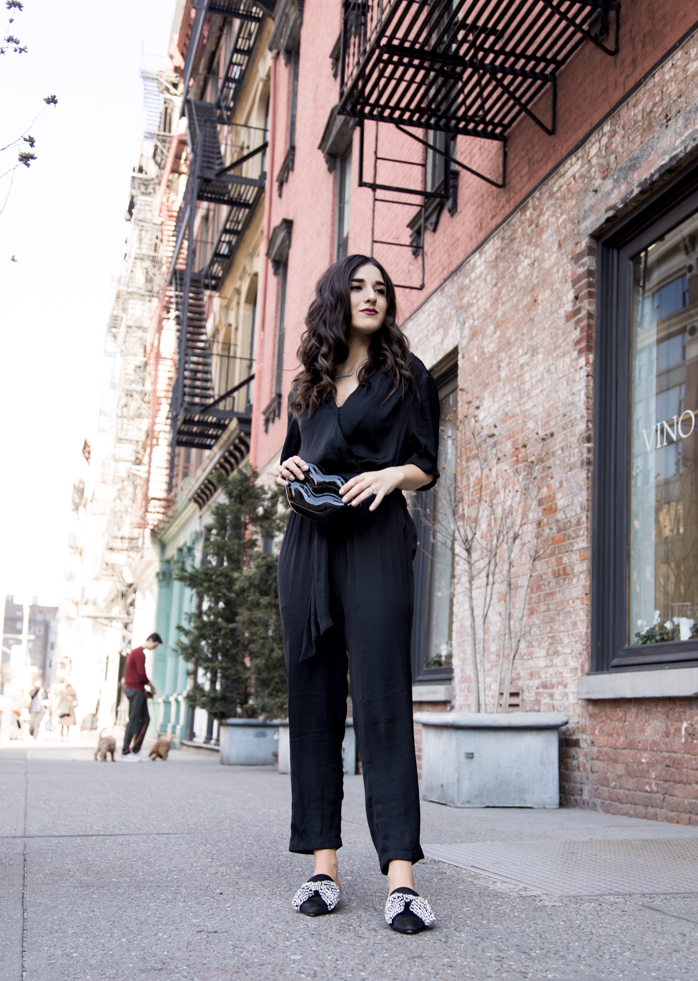 Where We're Going For Our Honeymoon Black Silk Jumpsuit Bow Mules Esther Santer Fashion Blog NYC Street Style Blogger Outfit OOTD Trendy Urban Outfitters Betsey Johnson Soho Collab Jeweled  Shoes Earrings Braid Hairstyle Hoops Necklace Lips Clutch Bag.jpg