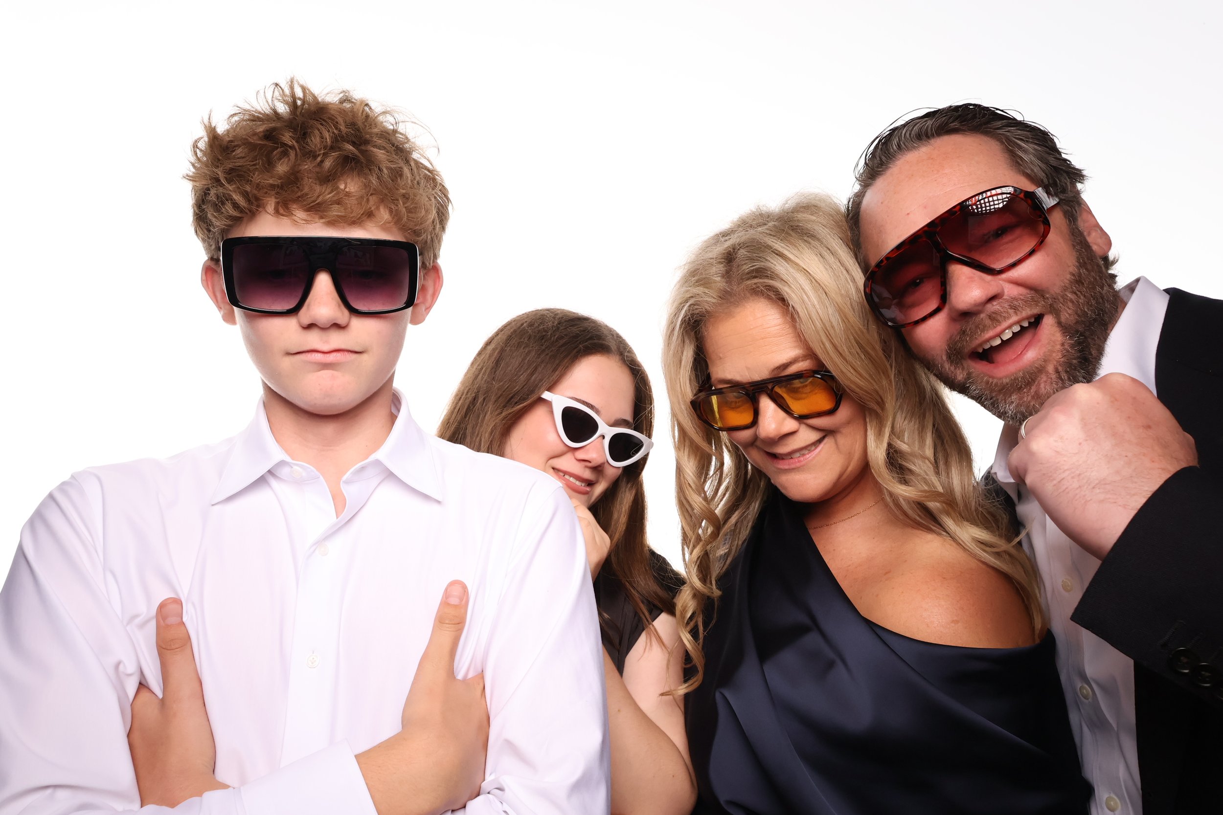 Family booth pictures of a group of four people wearing sunglasses, posing together with a white background.