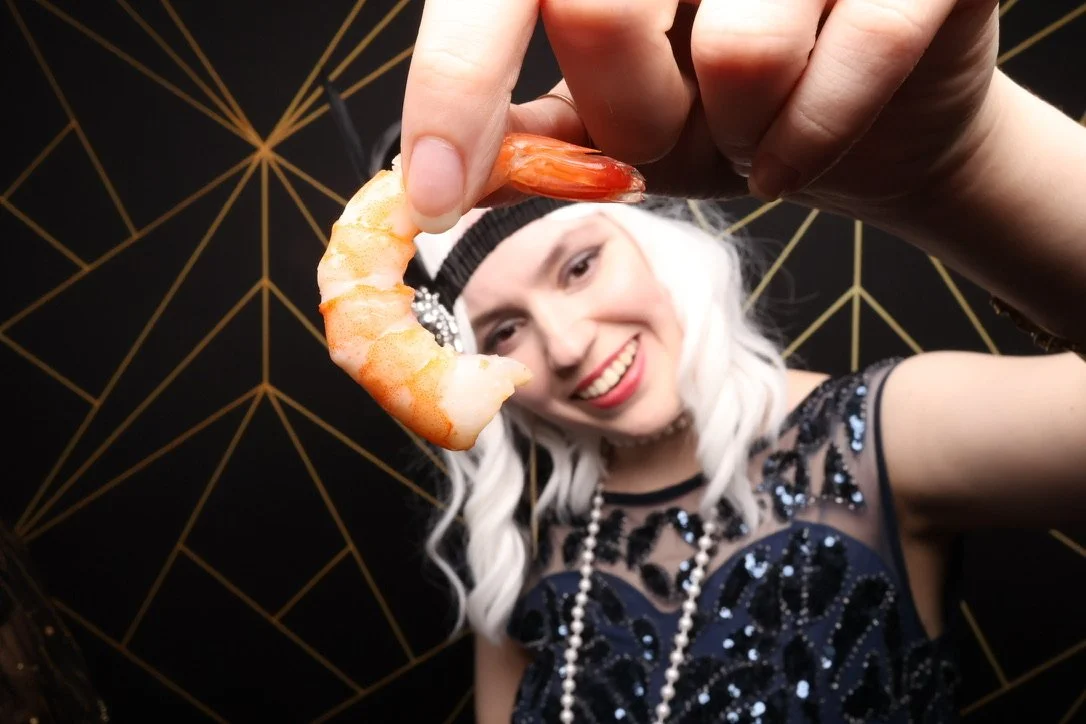 a woman who thinks a shrimp is a good photo booth prop