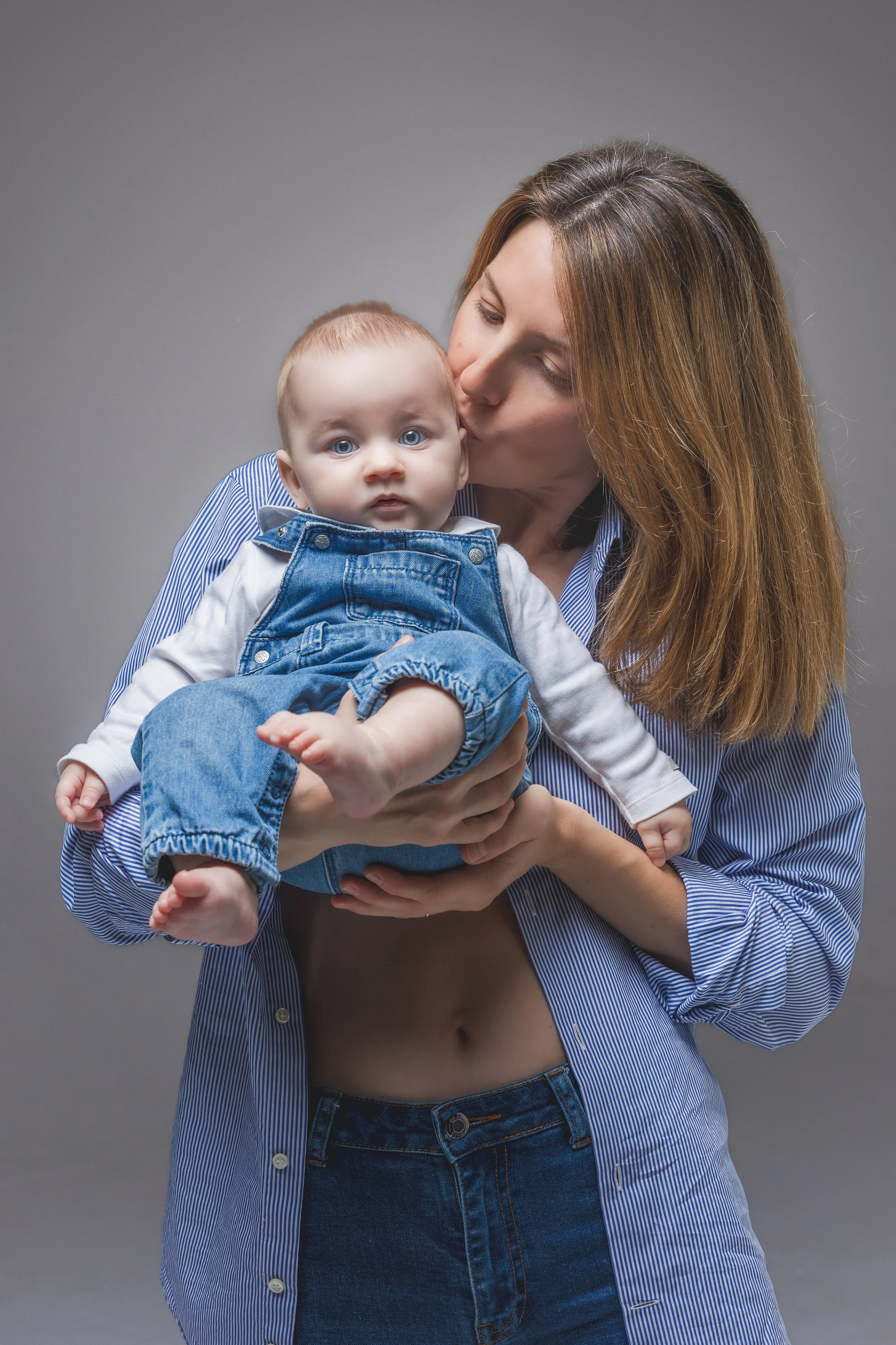 Ritratto di famiglia in studio a Milano, con mamma in camicia azzurra che tiene in braccio il suo bambino di circa sei mesi.