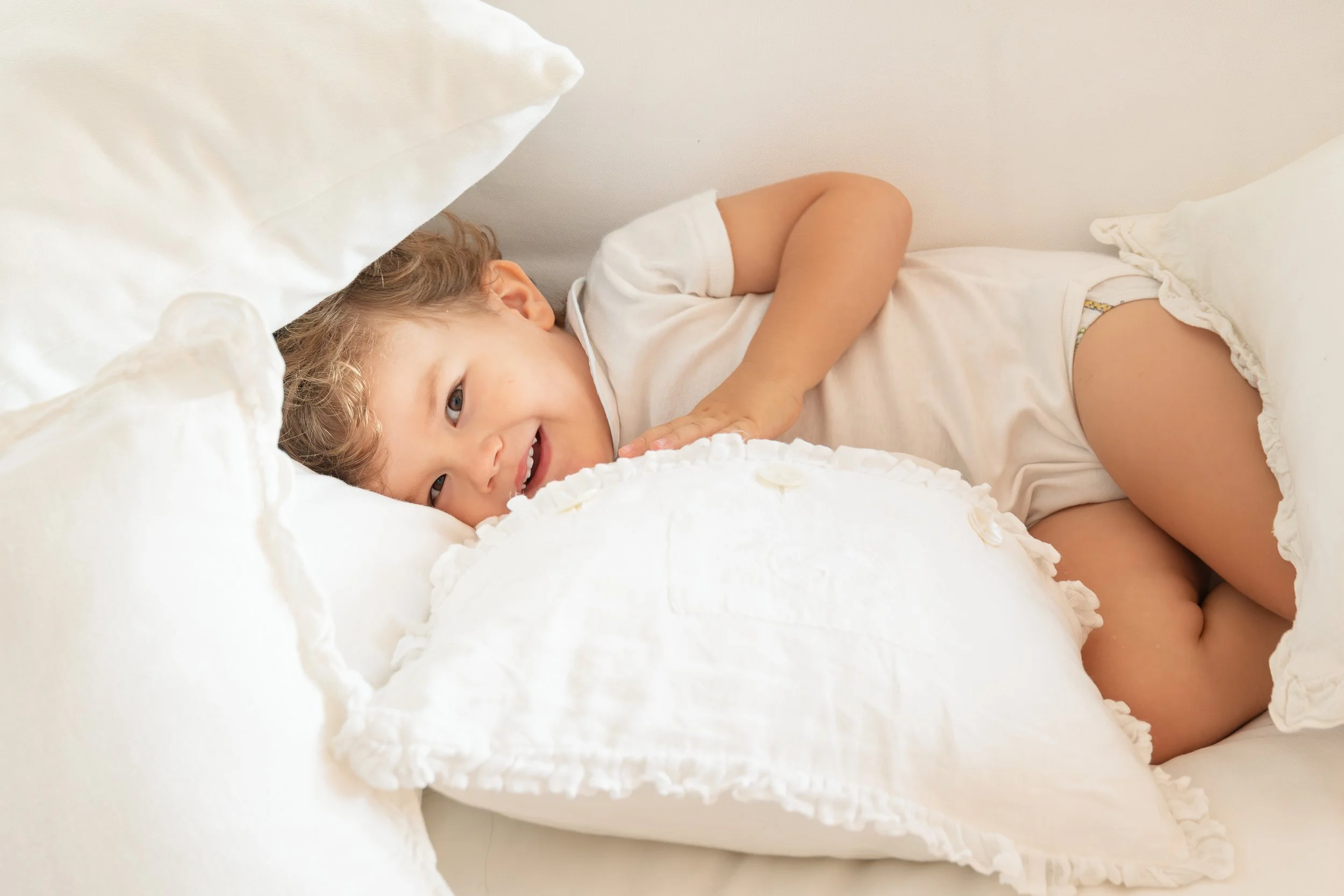 Bambino sorridente sul divano durante un servizio fotografico di famiglia a casa a Milano.
