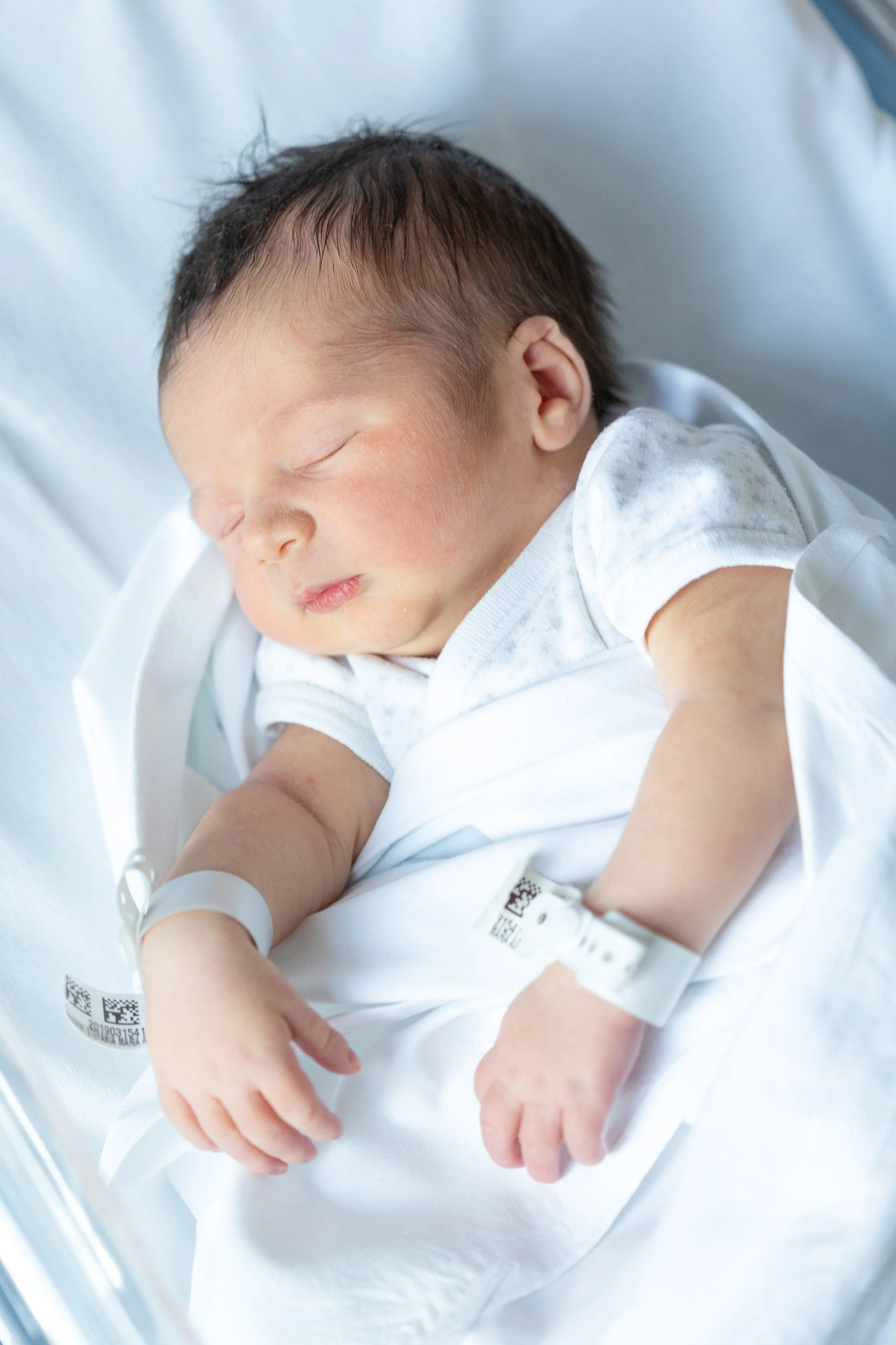 Fotografia di neonato nei primissimi giorni in ospedale a Milano, addormentato nella culla.