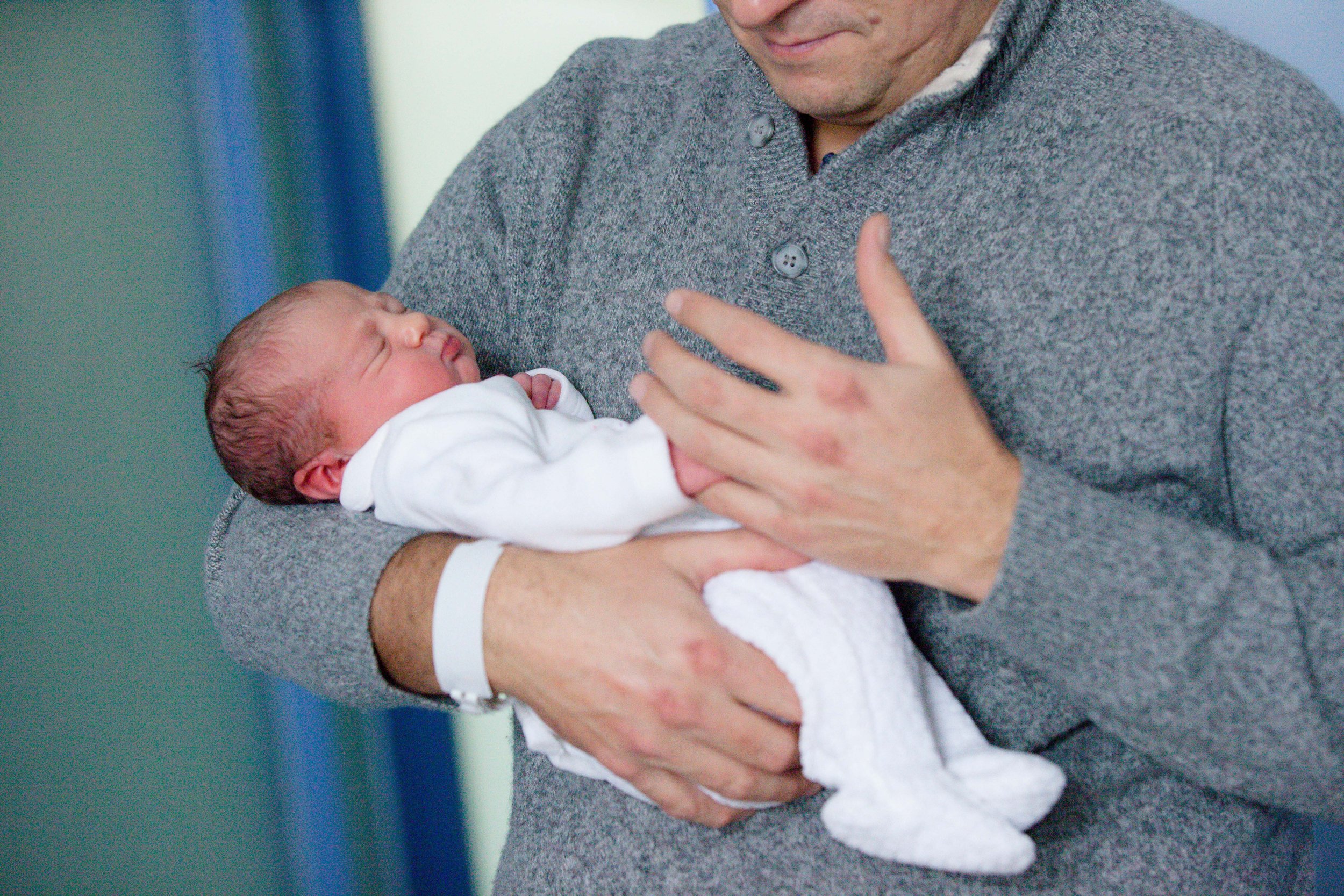 Fotografia di neonato nei primissimi giorni in ospedale a Milano, tra le braccia del papà.