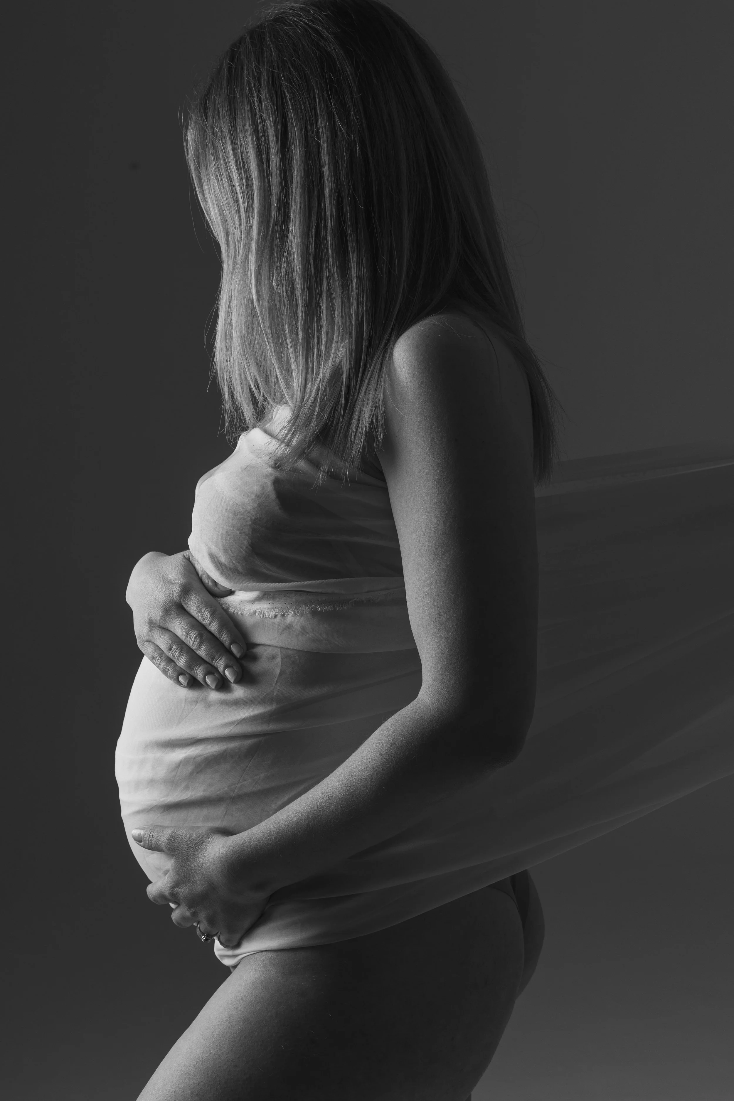 Ritratto fotografico di gravidanza in studio a Milano, con futura mamma alla 36ª settimana fotografata in silhouette.