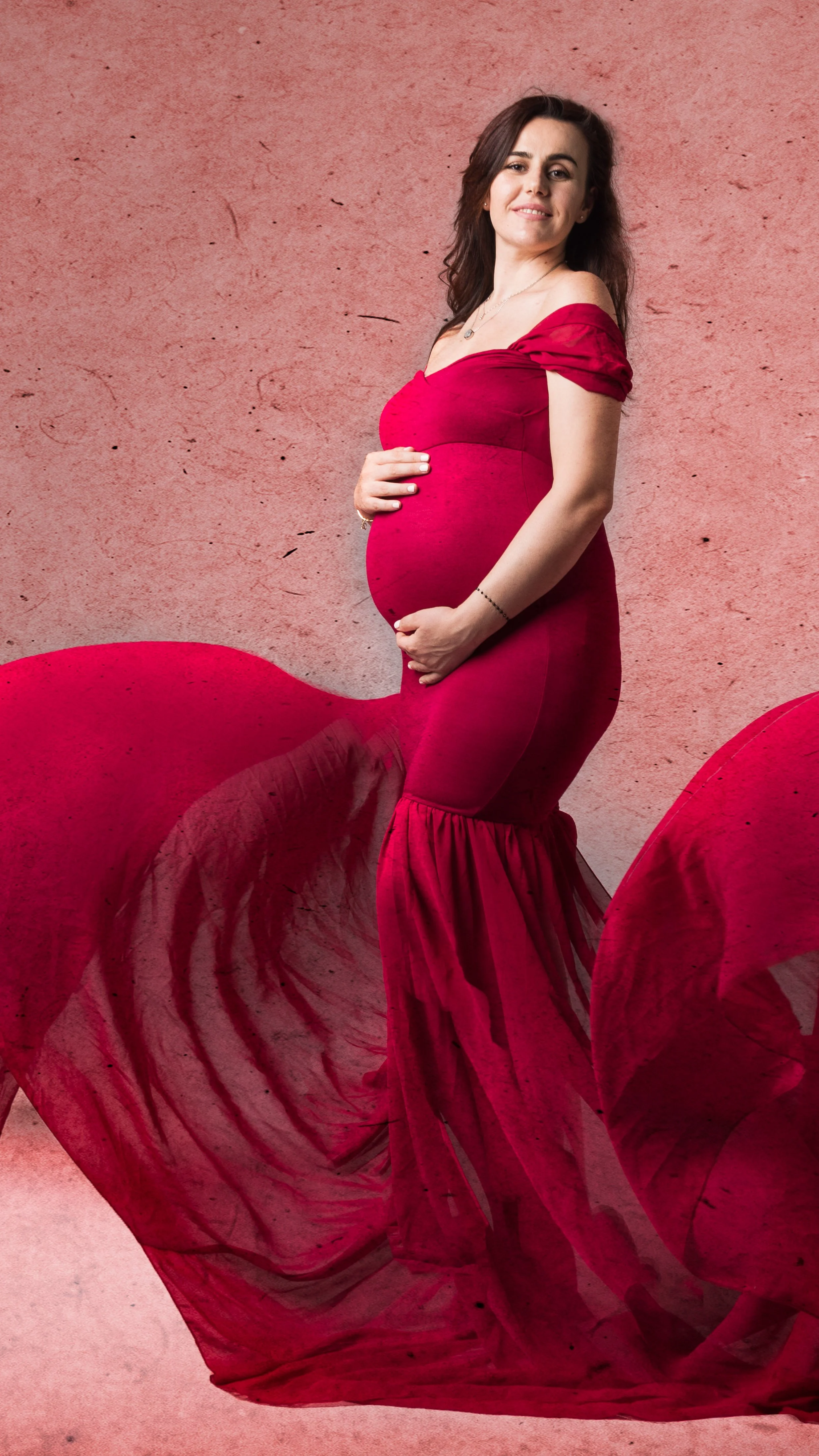 Ritratto fotografico di gravidanza in studio a Milano, con futura mamma in abito rosso pochi giorni prima del parto.