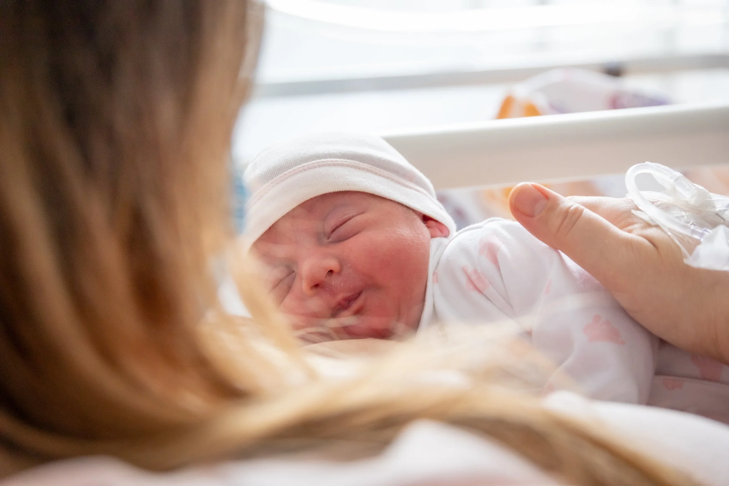 Ritratto di maternità nei primissimi giorni alla Mangiagalli di Milano, con neonato nella culla accanto alla mamma.