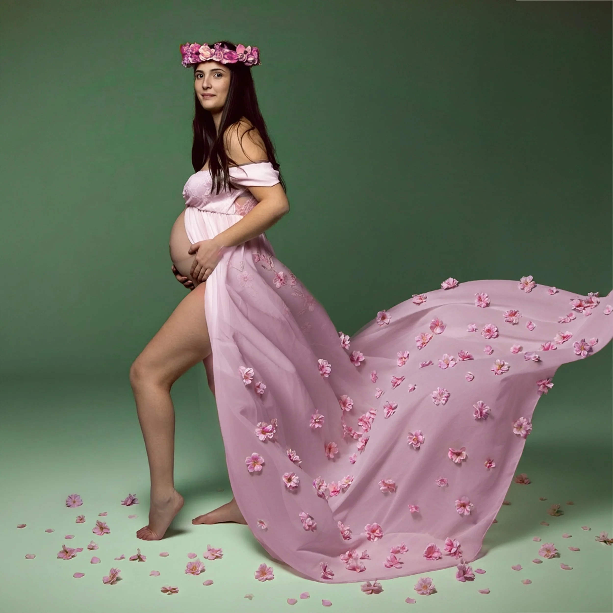 Ritratto fotografico di gravidanza in studio a Milano, con futura mamma in abito rosa decorato con fiori.