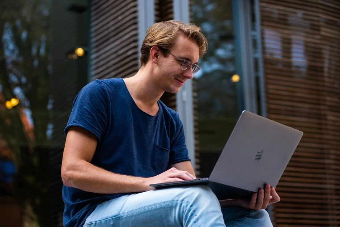 A man sitting outside with a laptop computer
