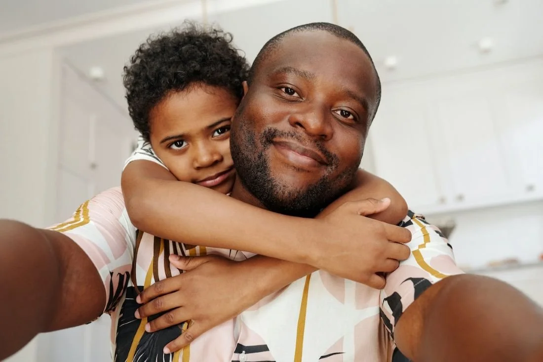 Father with child behind with arms around father