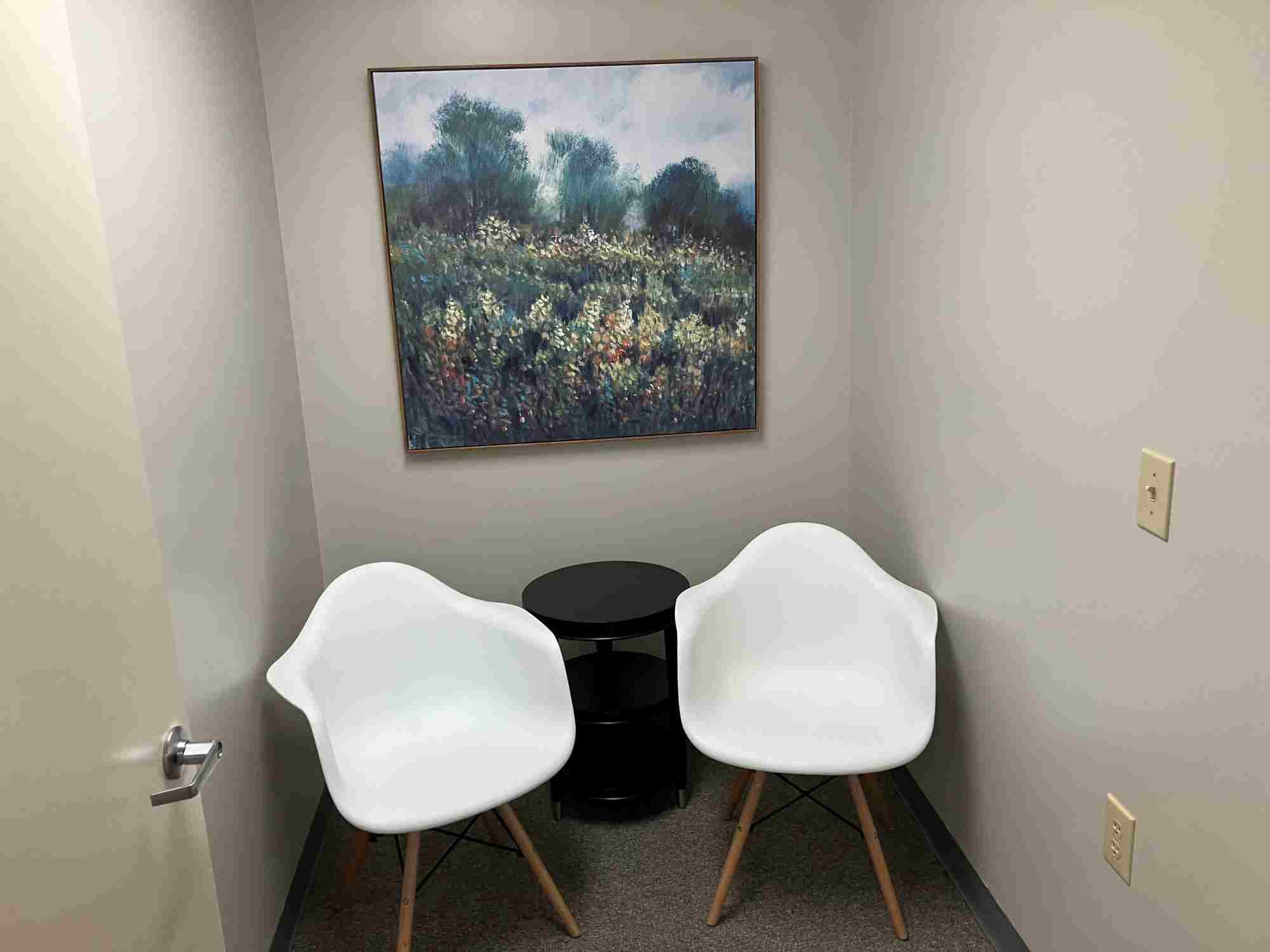 2 chairs in waiting room in front of painting